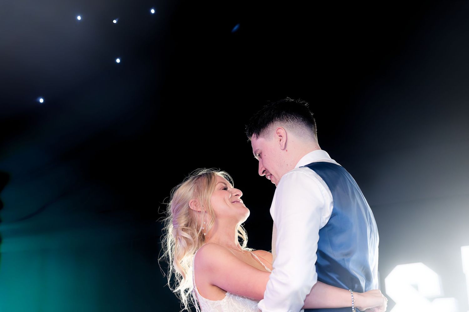Bride and groom sharing a romantic first dance under a starry night sky at their wedding.