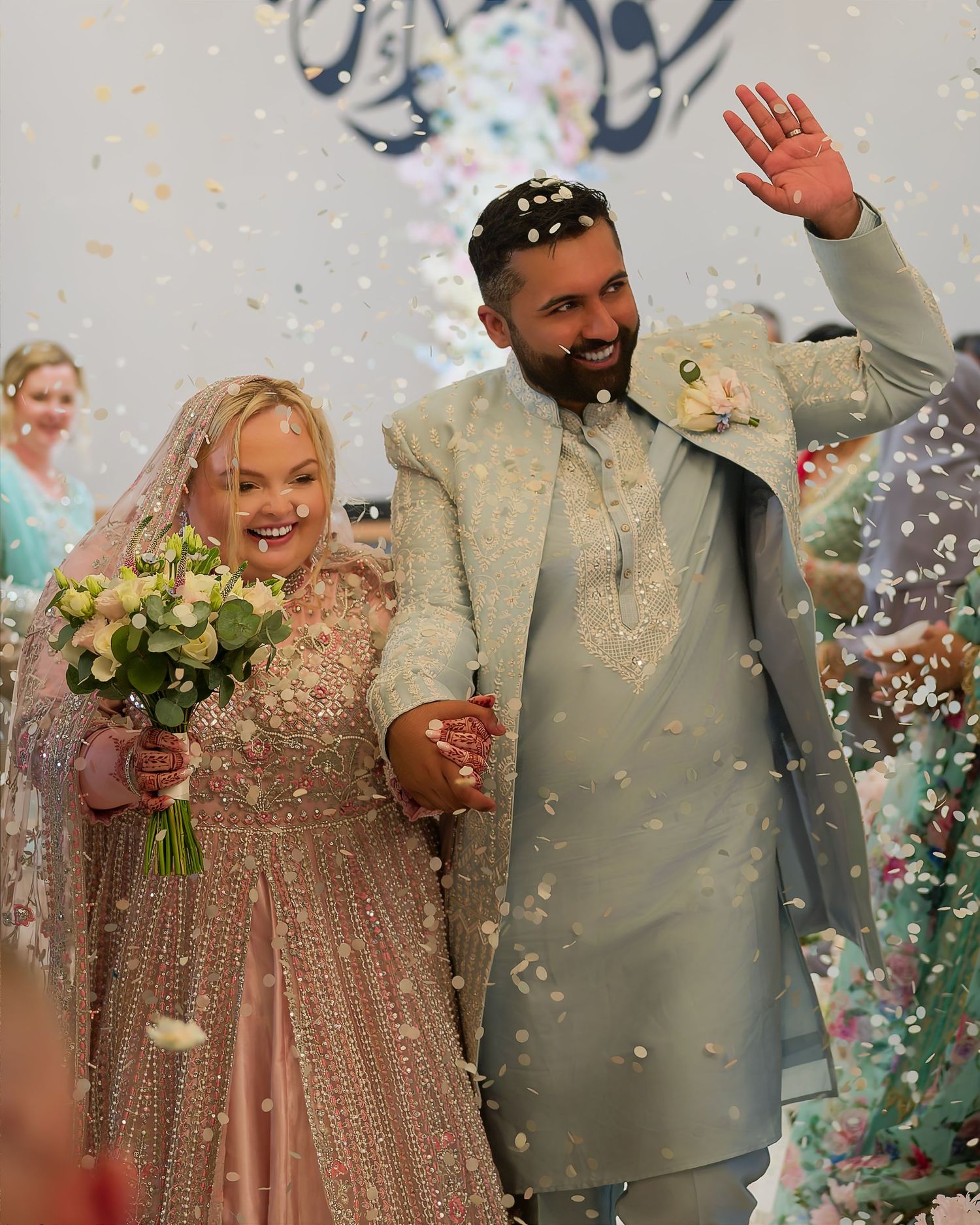 Bride and groom walking down aisle through confetti shower after wedding ceremony.