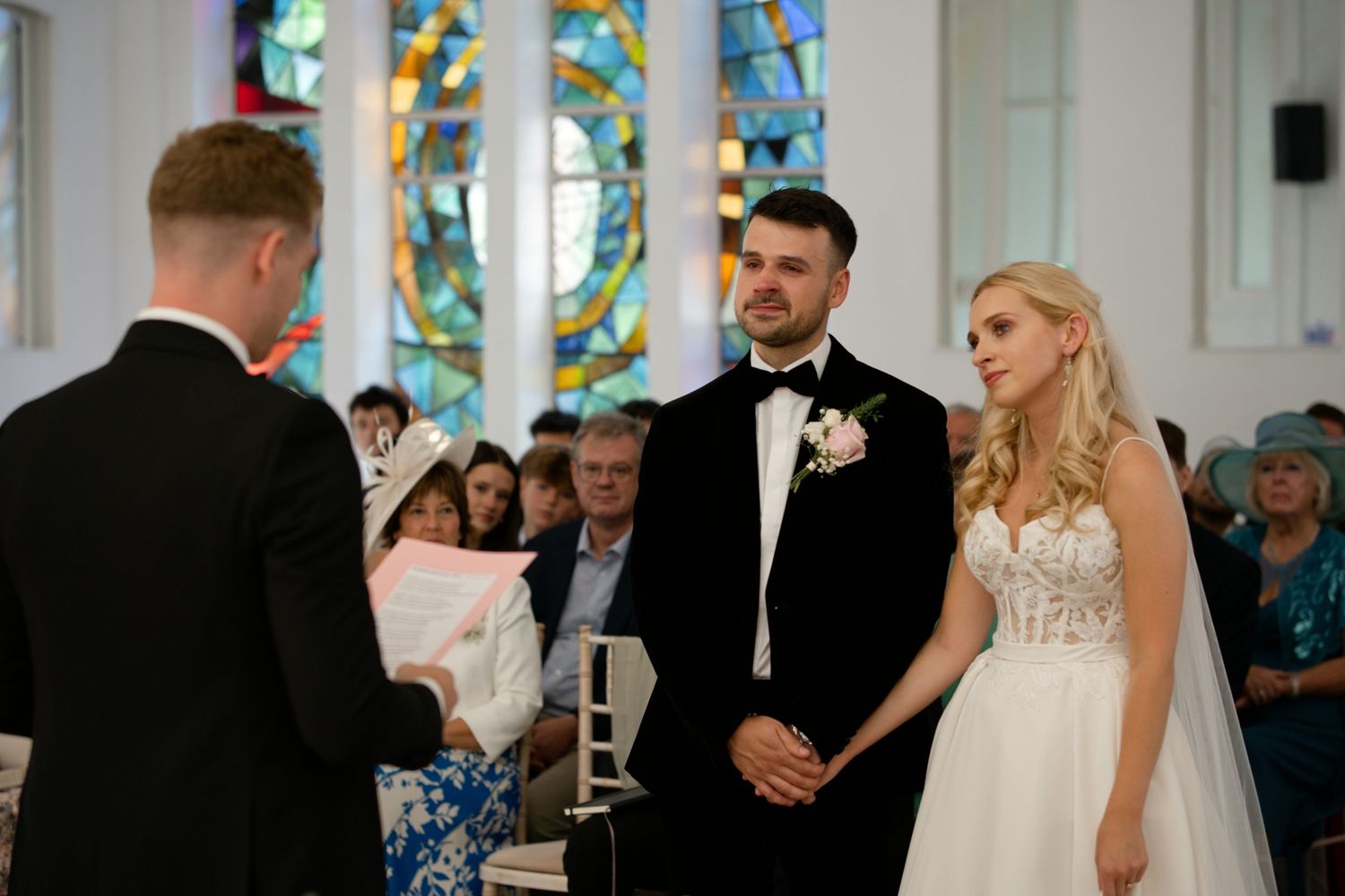Bride and groom standing at altar with officiant during church wedding ceremony.