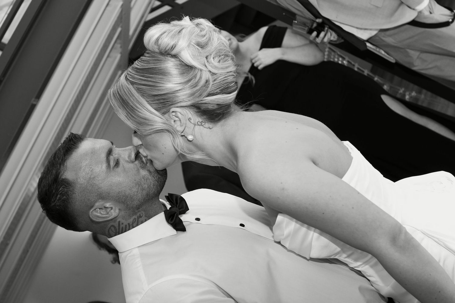 Black and white photo of a bride and groom sharing a romantic kiss at their wedding reception.