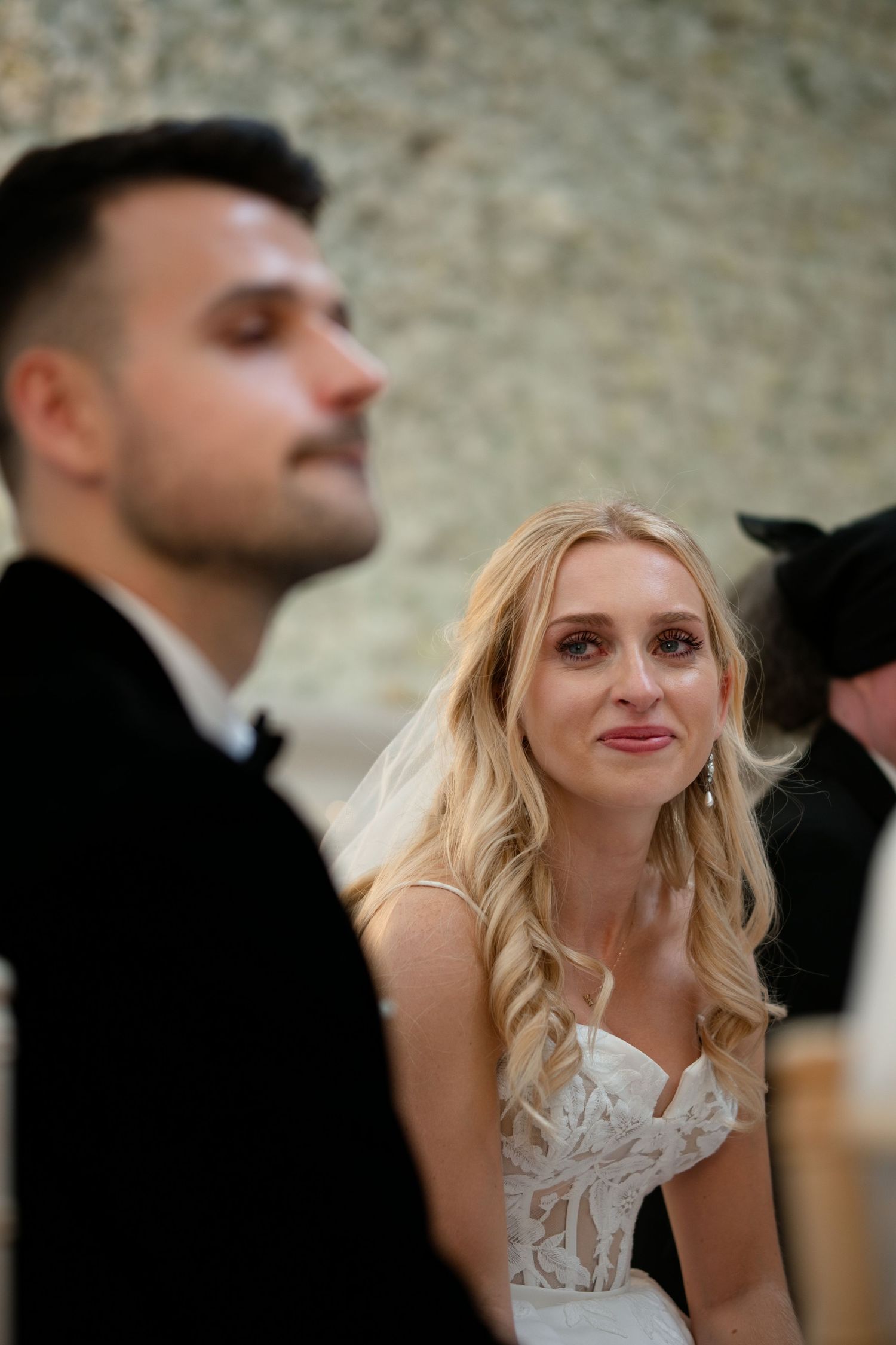 Emotional blonde bride in lace gown during wedding ceremony.