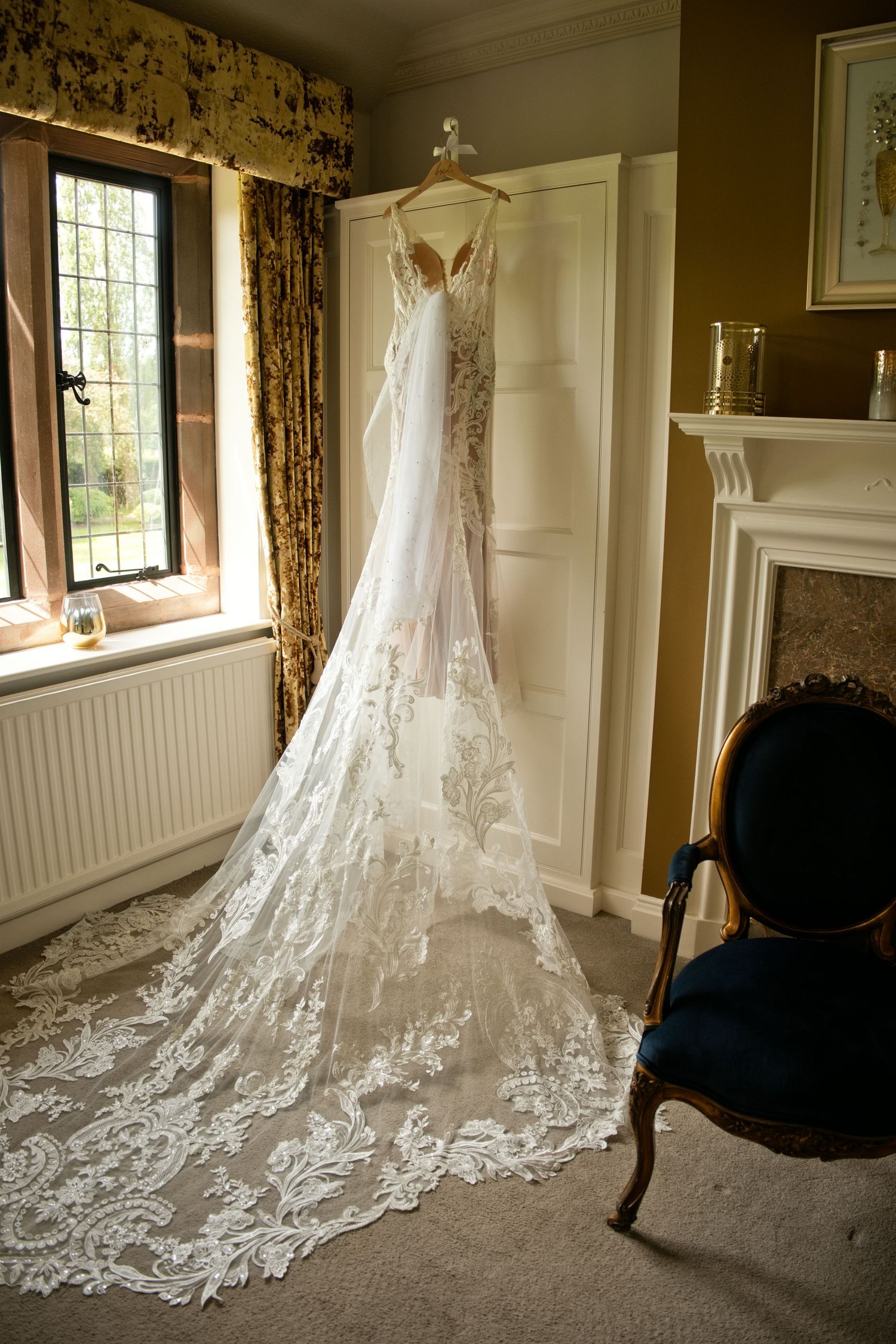 Elegant lace wedding dress with long train hanging in vintage room.