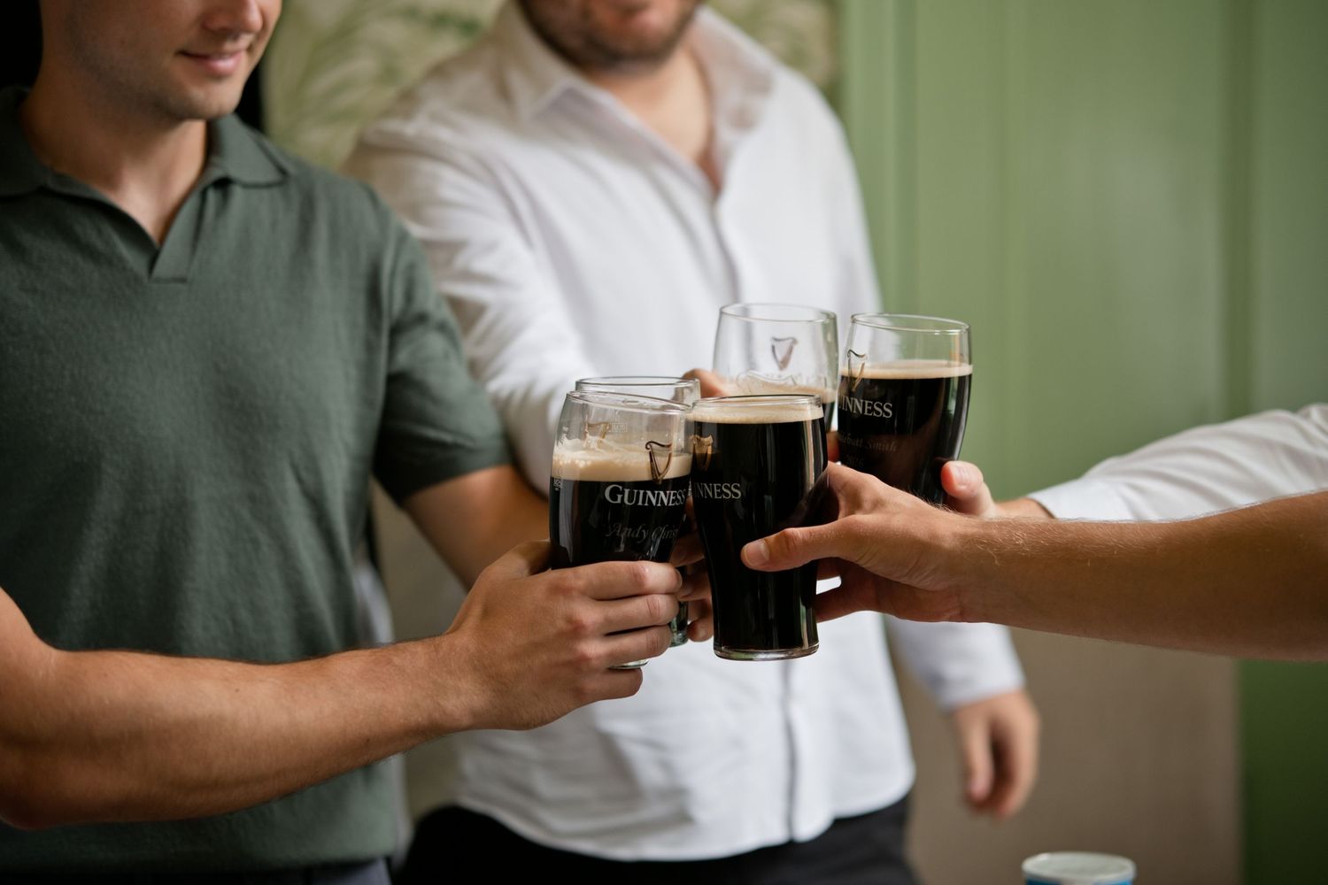 Groomsmen clinking pints of Guinness together in a celebratory toast before the wedding.