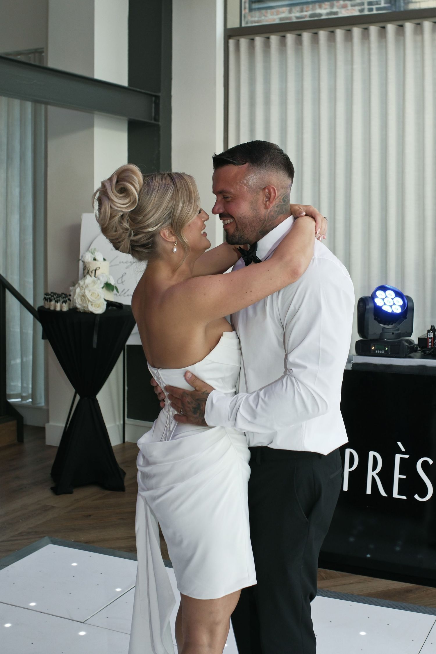 Bride and groom sharing first dance at elegant wedding venue with DJ setup.