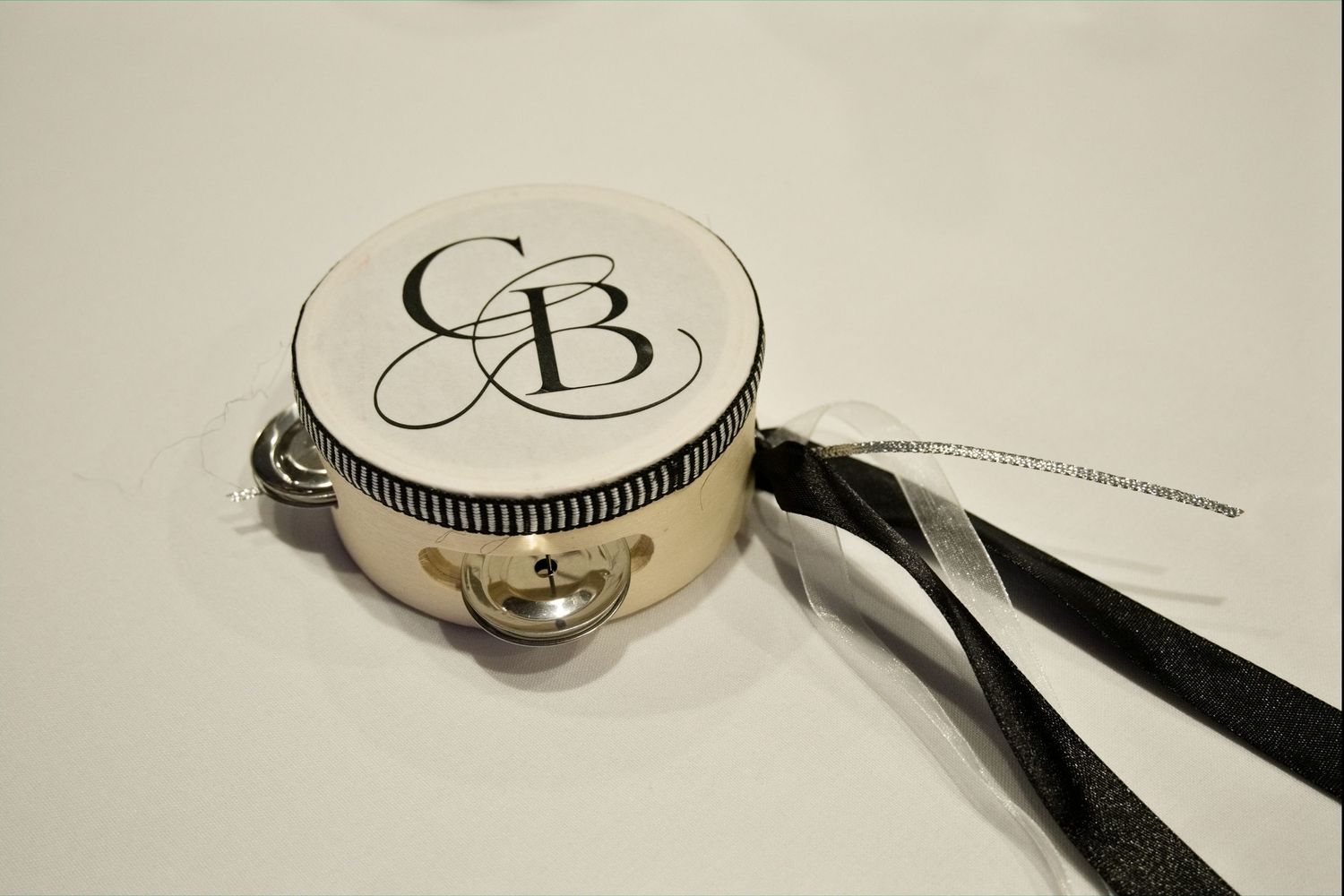 Custom monogrammed tambourine with CB initials and black ribbon as decorative wedding favor or accessory.