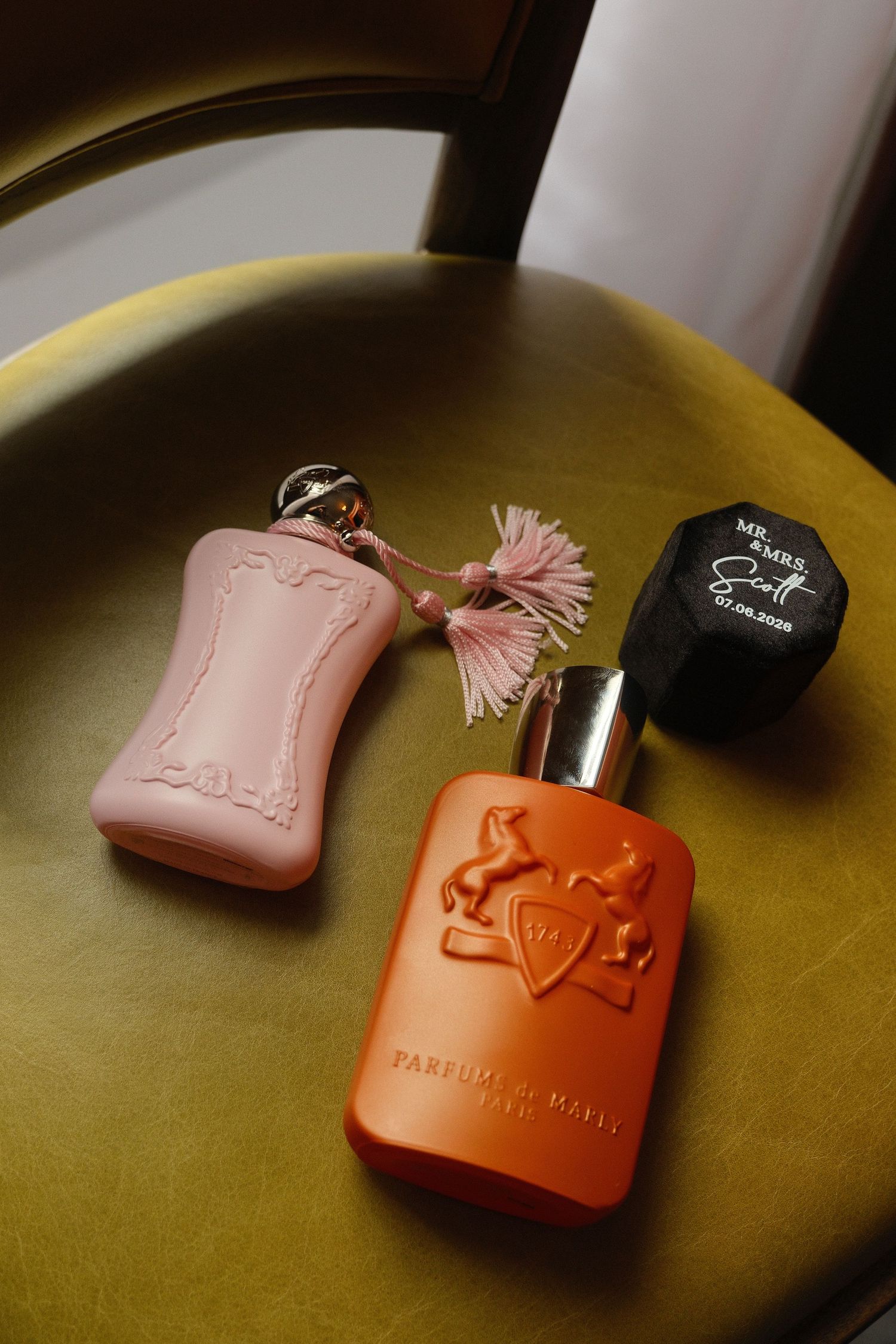 Two Parfums de Marly perfume bottles and personalized fragrance displayed on velvet chair.