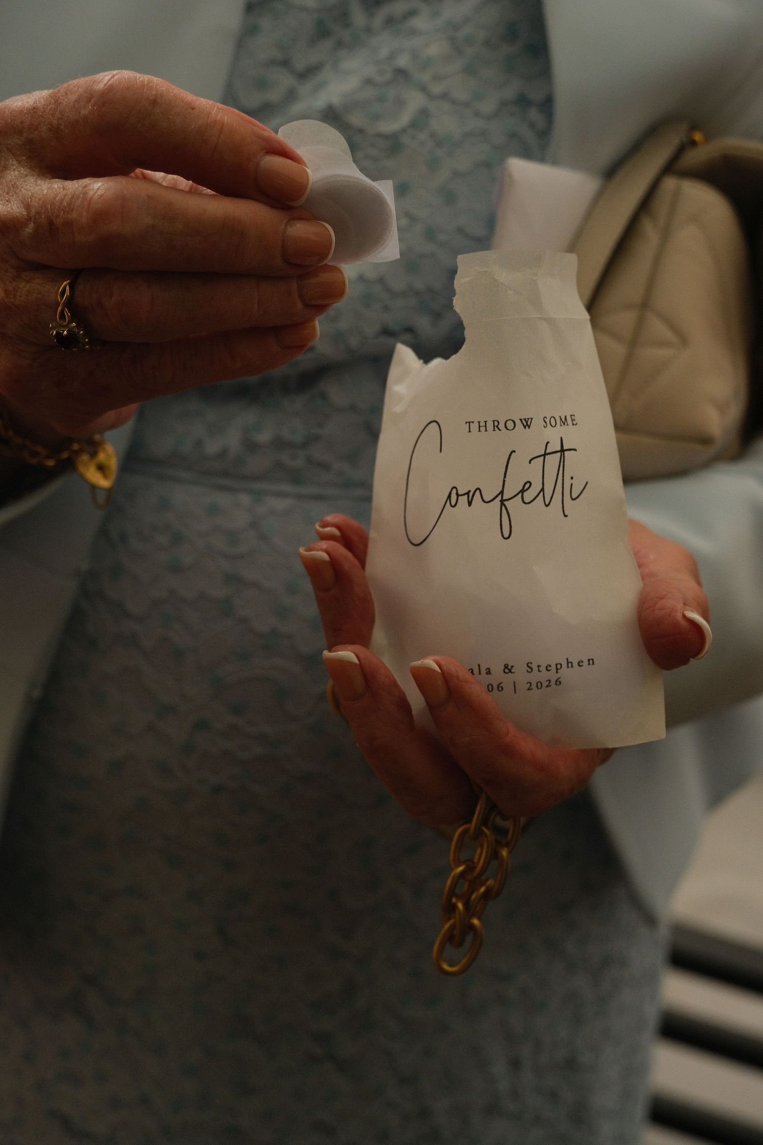 Guest holds personalized confetti packet reading Throw Some Confetti for Isla and Stephen wedding celebration.