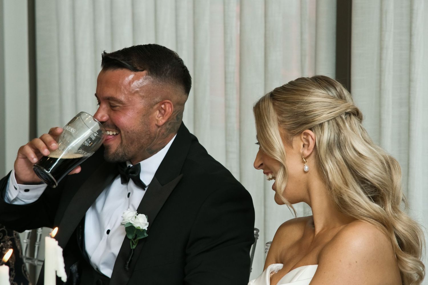 Bride and groom laughing and toasting with champagne at wedding reception.