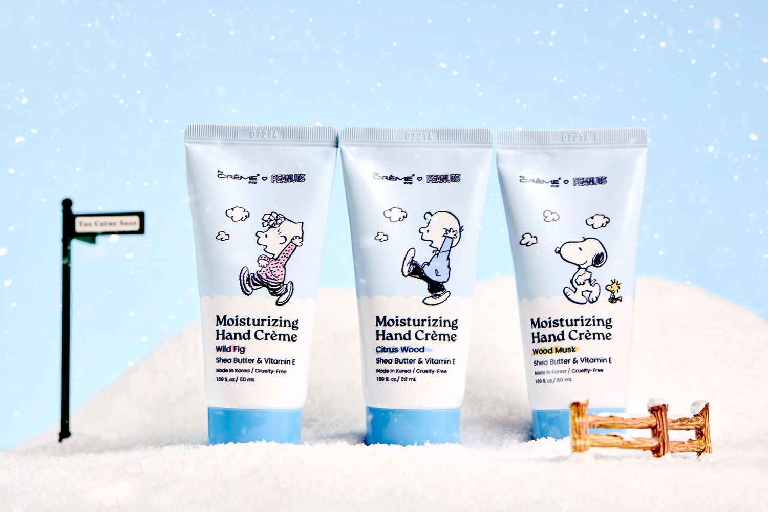 Three Snoopy Peanuts Moisturizing Hand Crème tubes displayed in snow with shea butter and vitamin E formula.