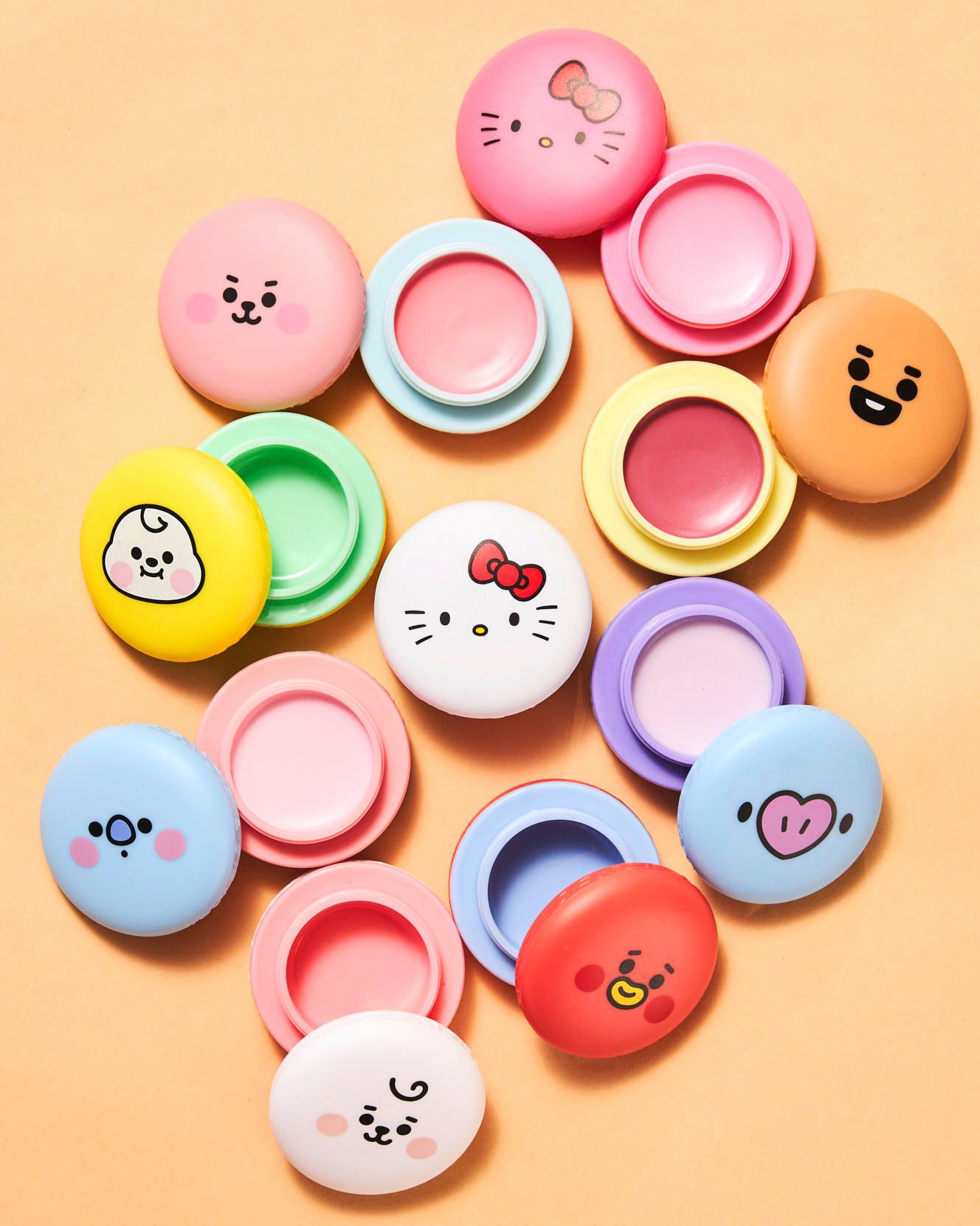 Cute cartoon character lip balm tins open to reveal colorful balms, featuring Hello Kitty and BT21 designs on orange background.