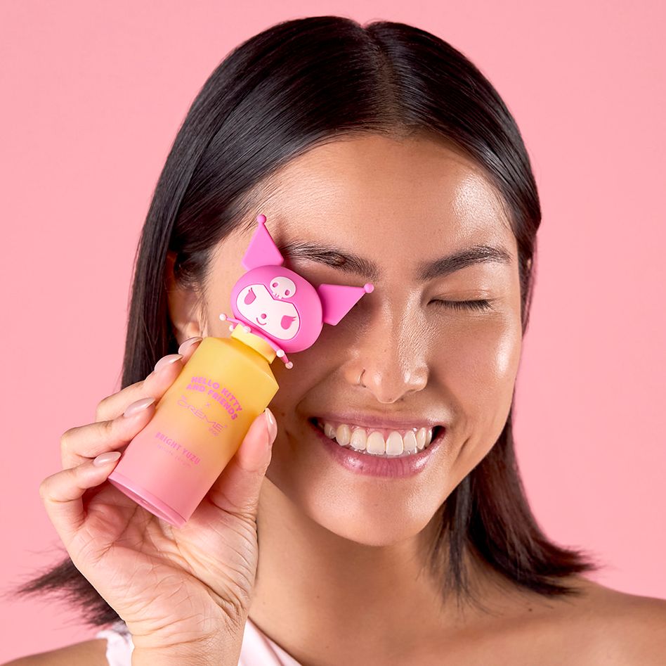 Smiling woman holding a pink My Melody Sanrio beauty product against her cheek on a pink background.