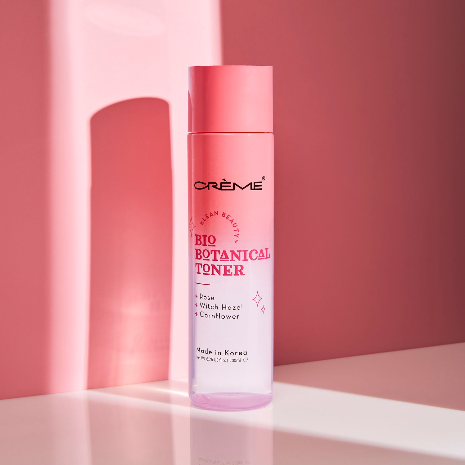 Crème Bio Botanical Toner bottle with rose, witch hazel, and cornflower, made in Korea, on pink background.