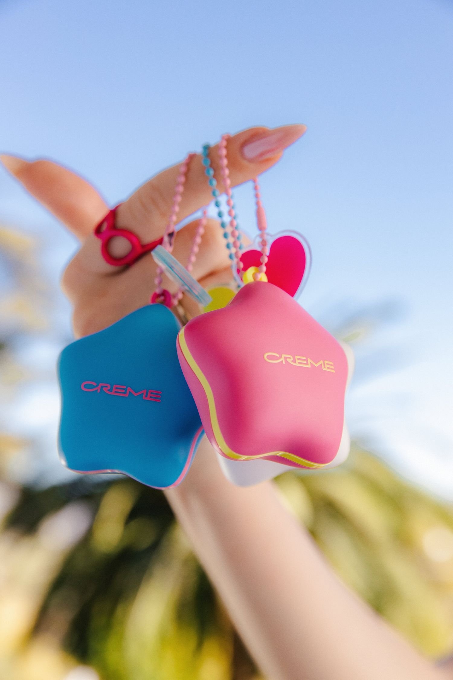 Lifestyle product shot of Creme beauty compacts against a blue sky by LA beauty photographer Belva Chan.