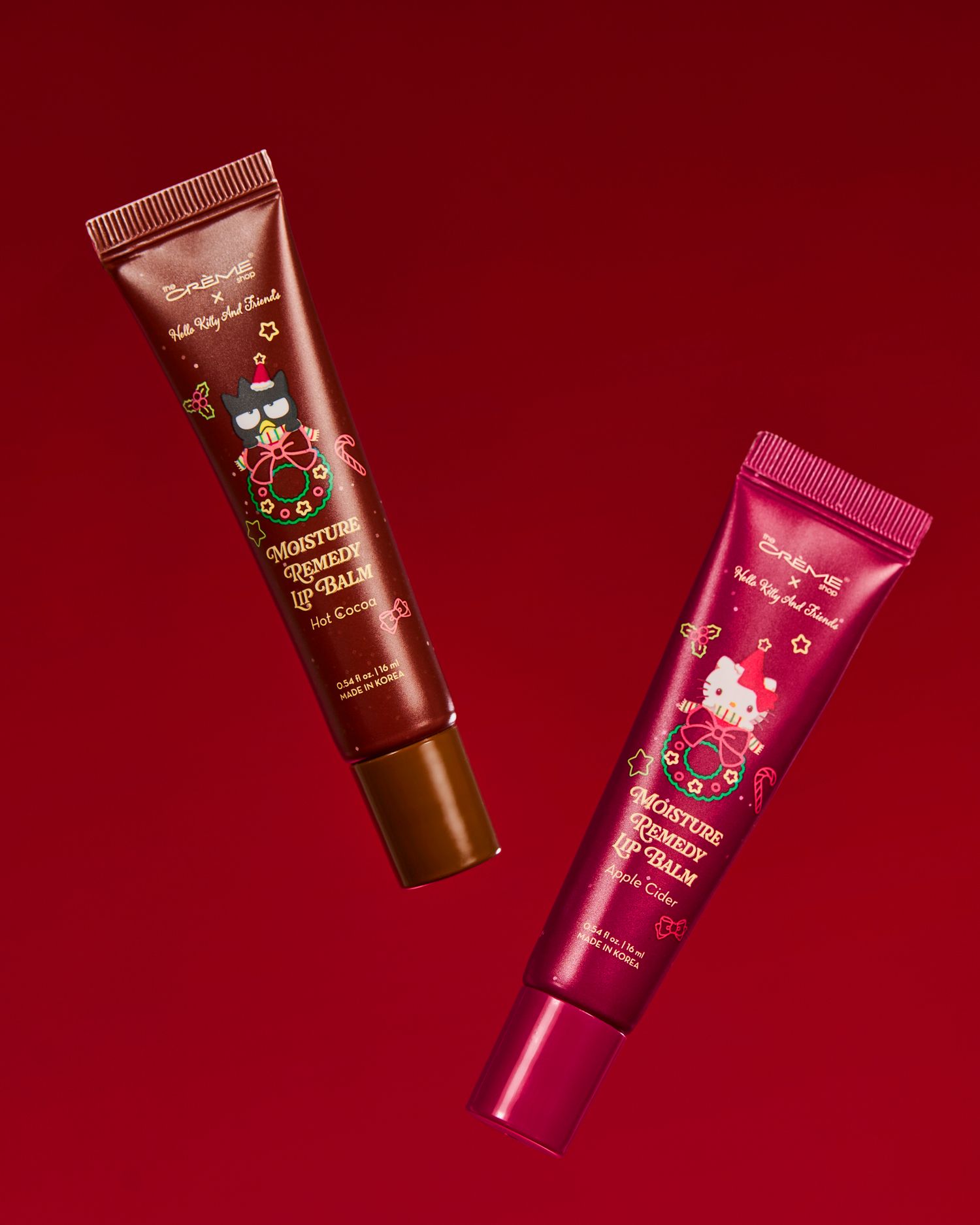 Two Hello Kitty holiday lip balm and serum tubes on a red background, featuring festive Christmas designs.