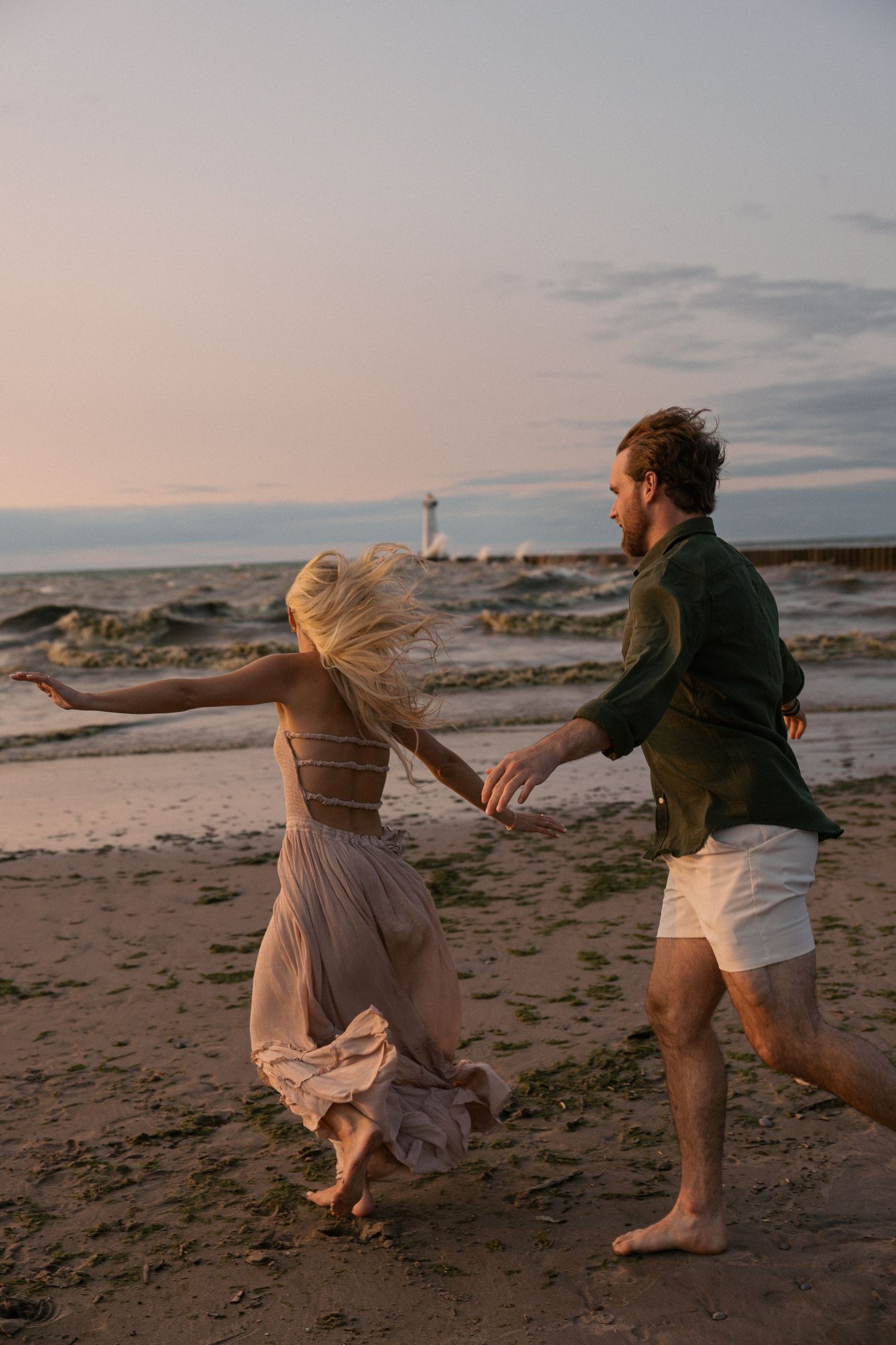 Couple running and playing together on a beach at sunset