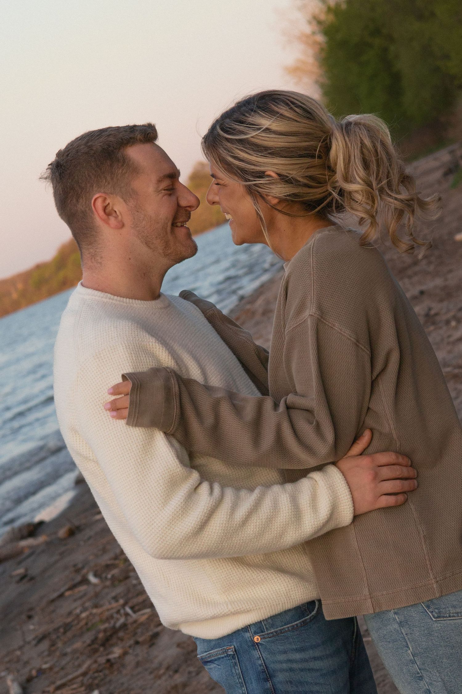 Couple laughing together beside the water during an outdoor photography session