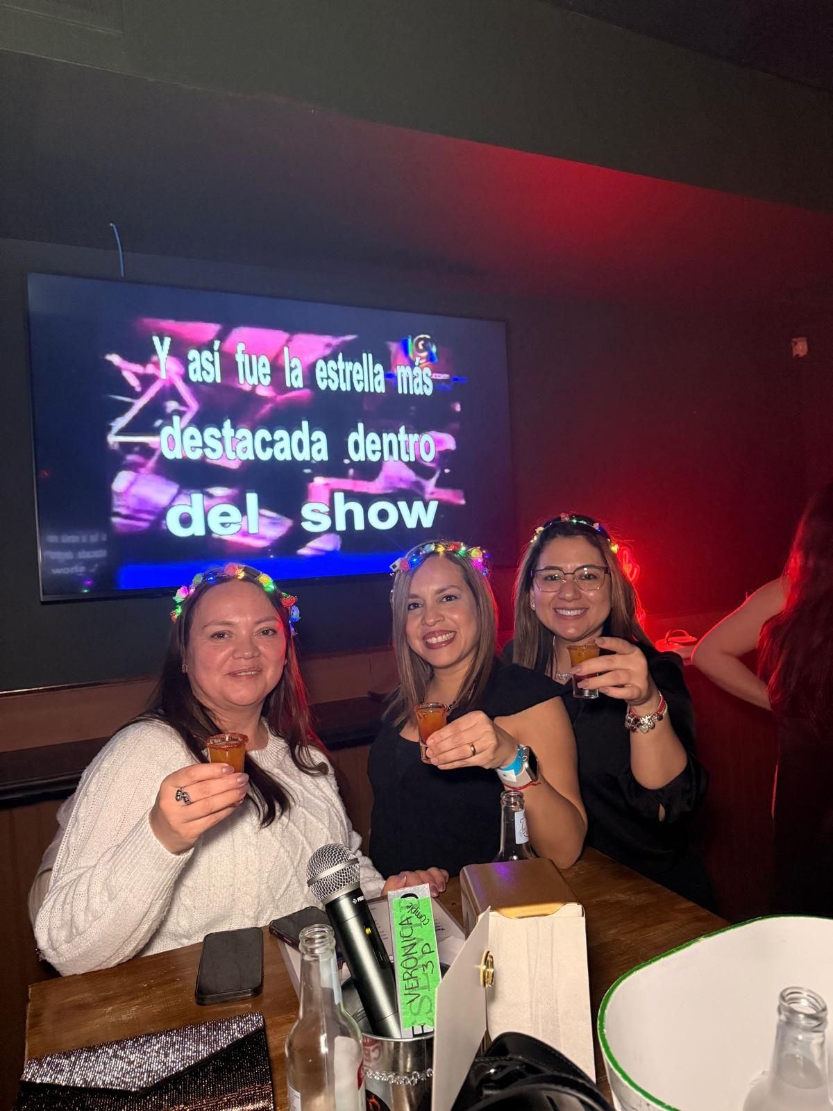 Friends enjoying a night out at a club with colorful neon lighting and drinks on the table.