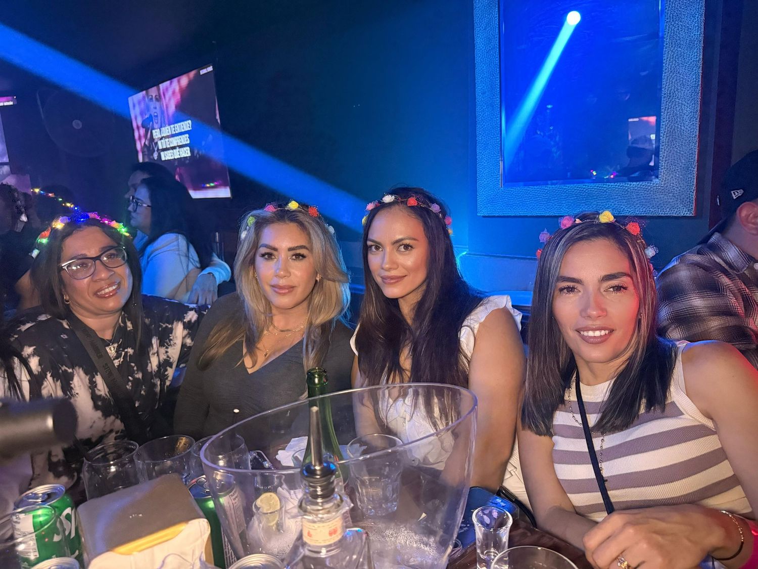 Group gathering at a bar with blue neon lighting and drinks on the table.
