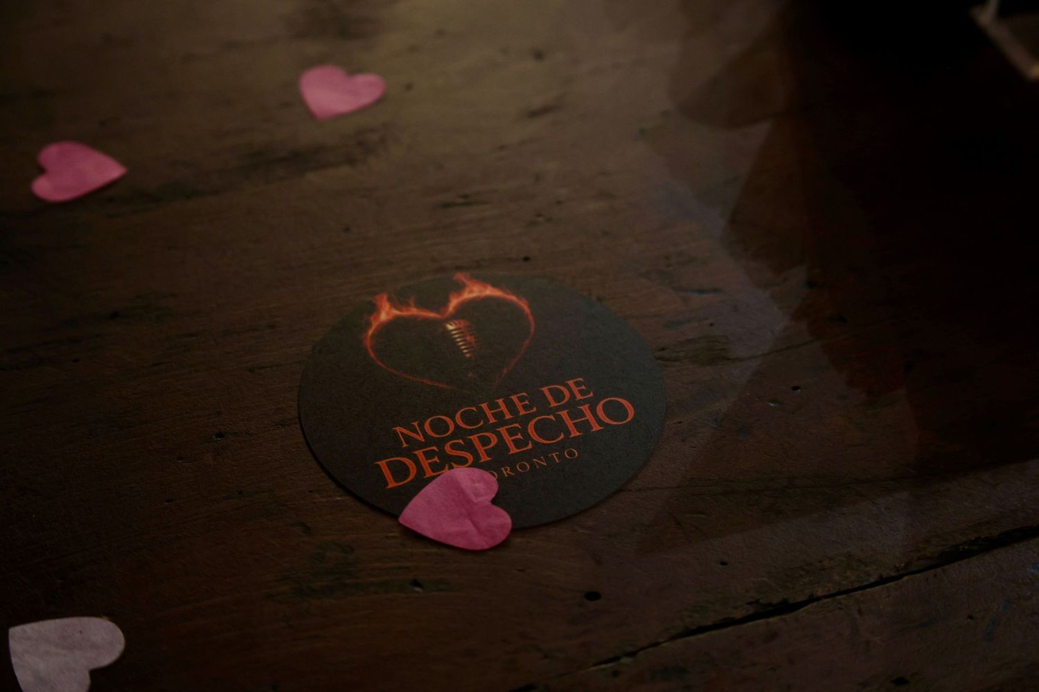 Pink heart decorations on a dark wooden surface create a romantic Valentine's Day atmosphere.