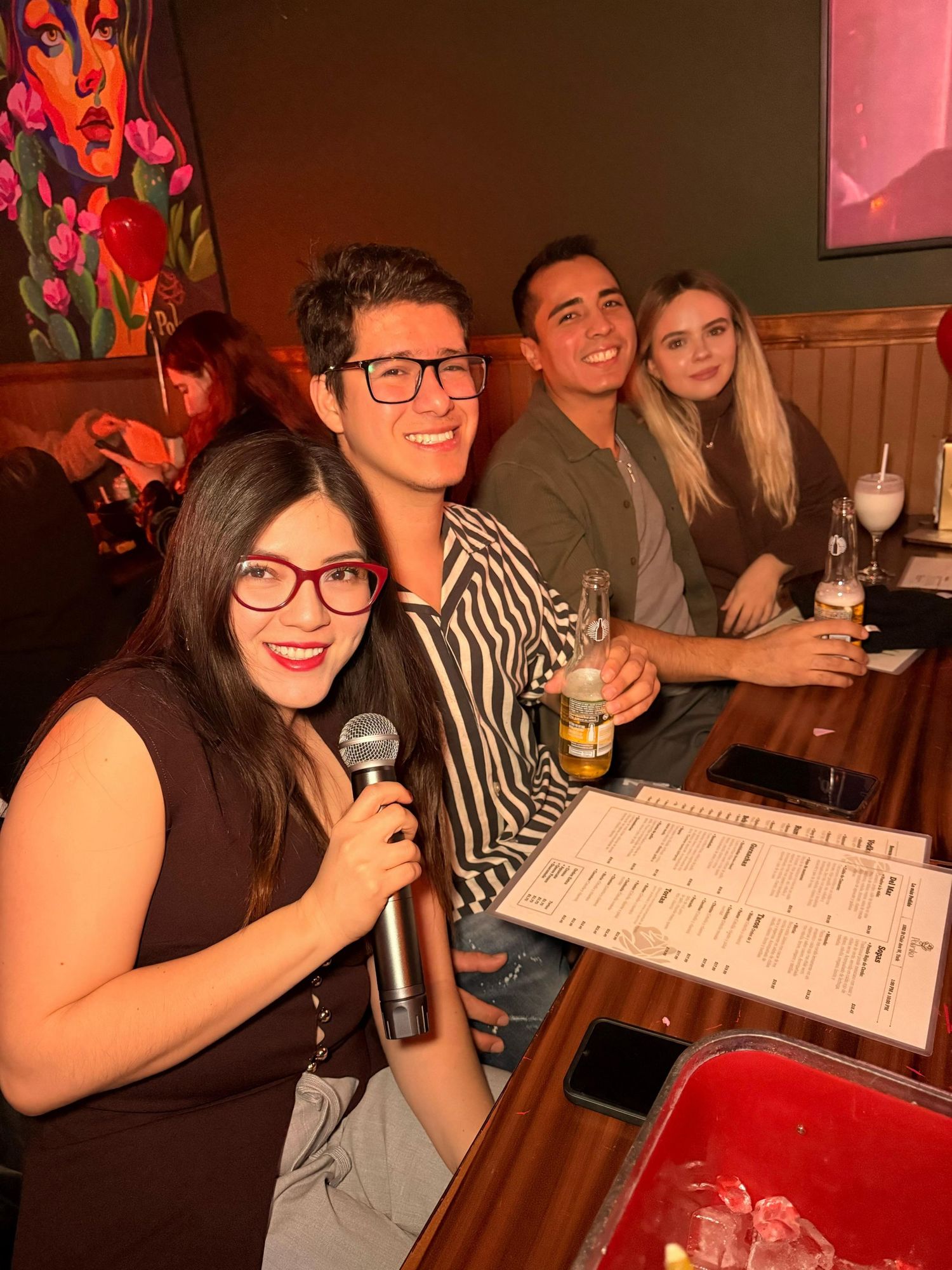 Friends enjoying karaoke night at a bar with drinks and microphone.