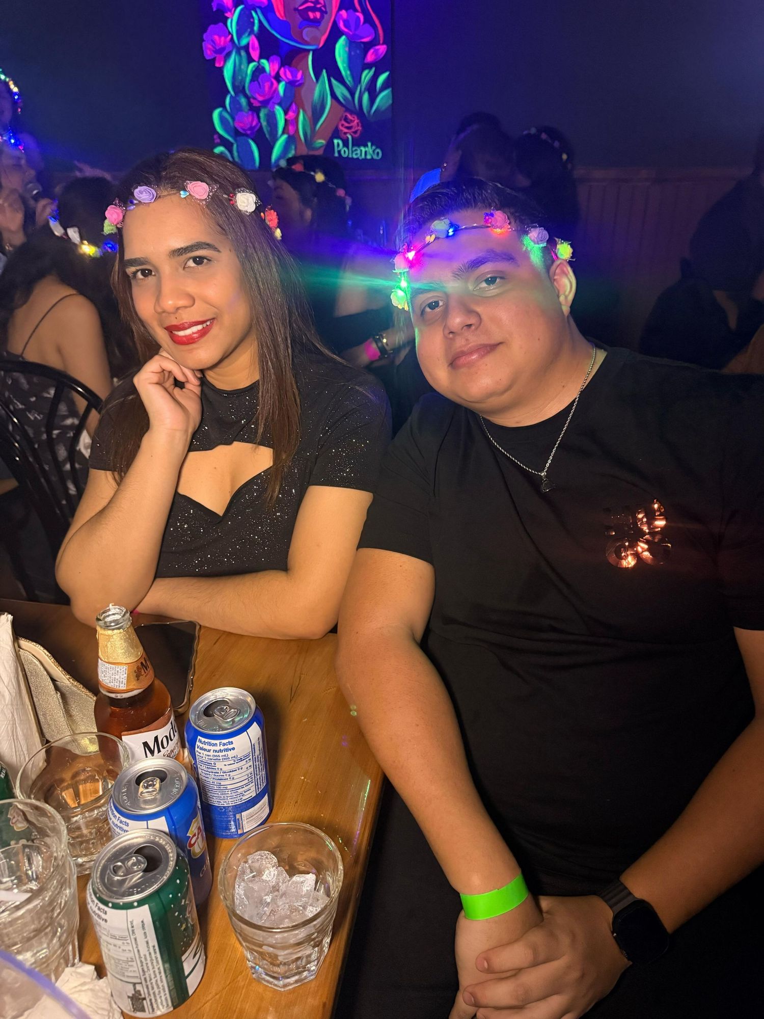 Friends gathered around a table with drinks under blue and purple neon lights.
