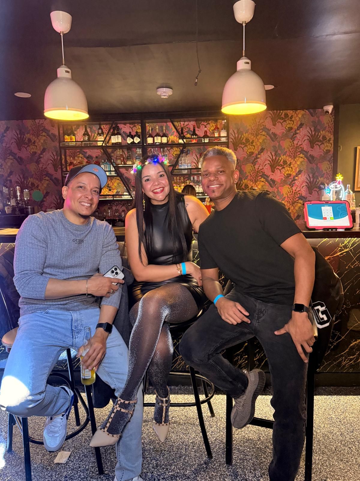 Group of friends gathered at a casual restaurant with vibrant wall art and pendant lighting in the background.