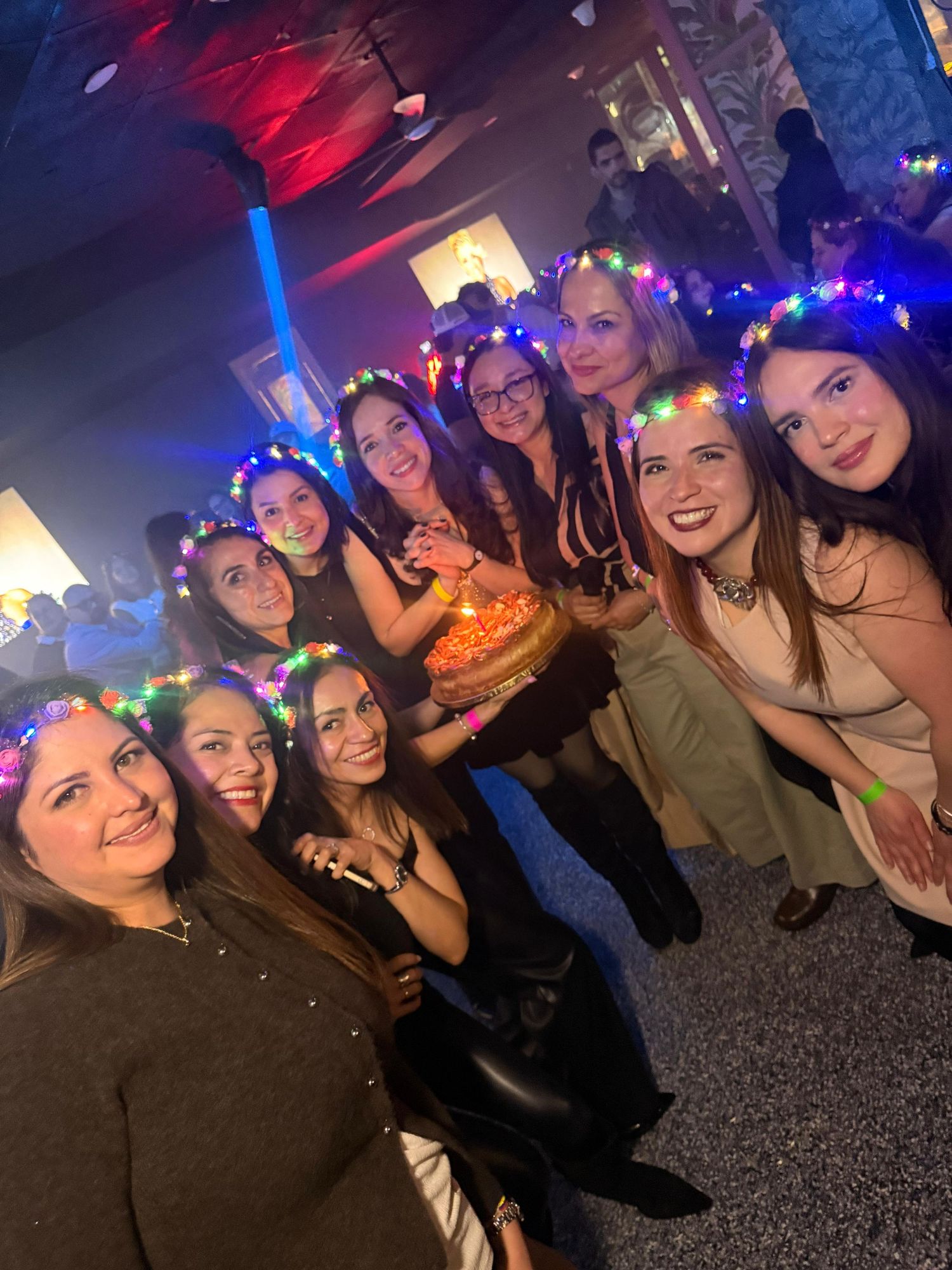 Large group photo at a nightclub with blue and red lighting effects.