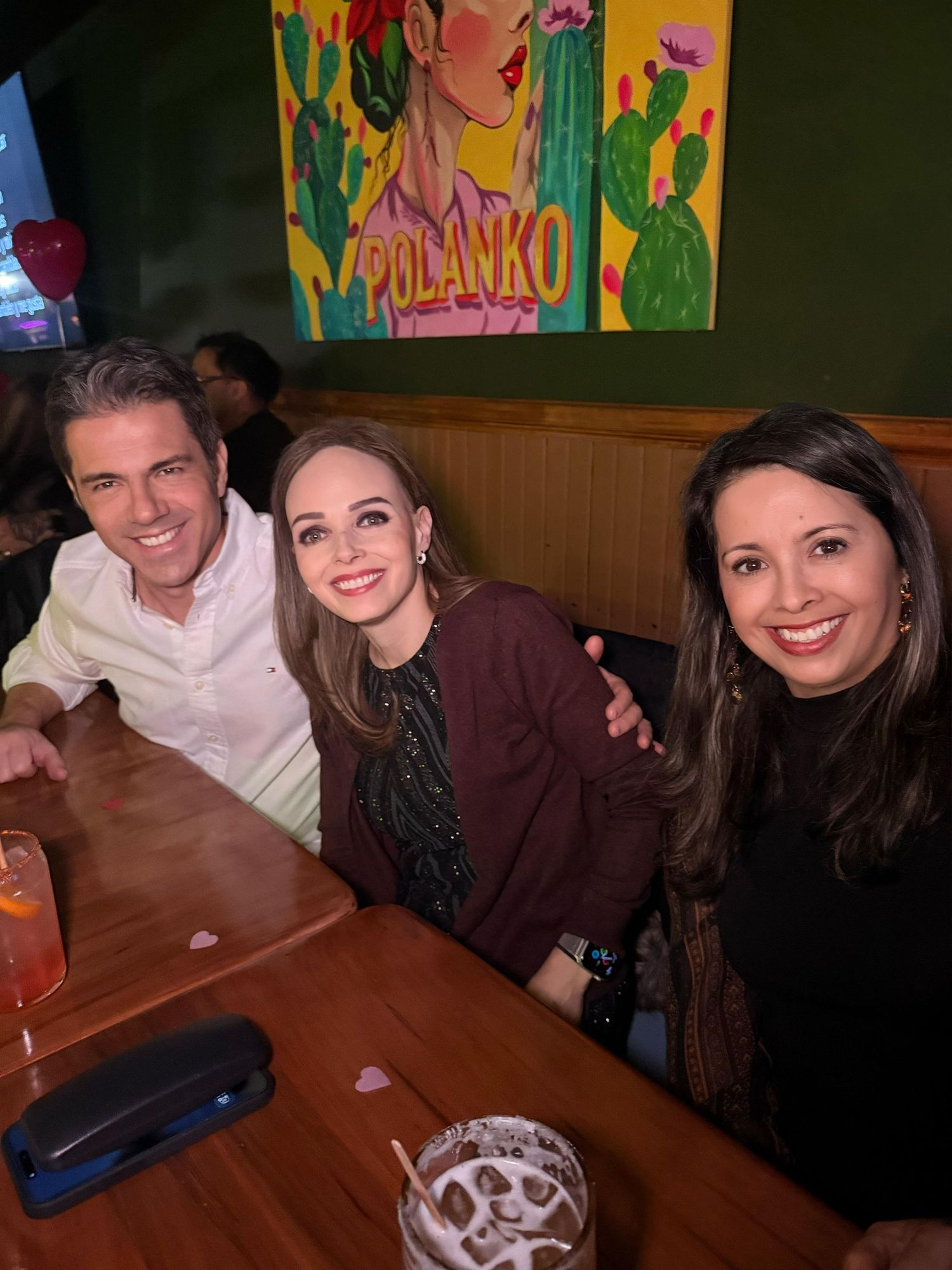Three people smiling at restaurant table with drinks.
