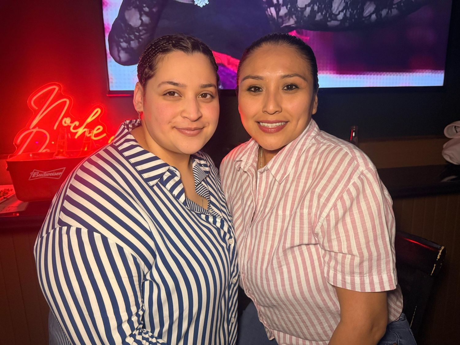 People in matching striped outfits enjoying a night out at a venue with red lighting.