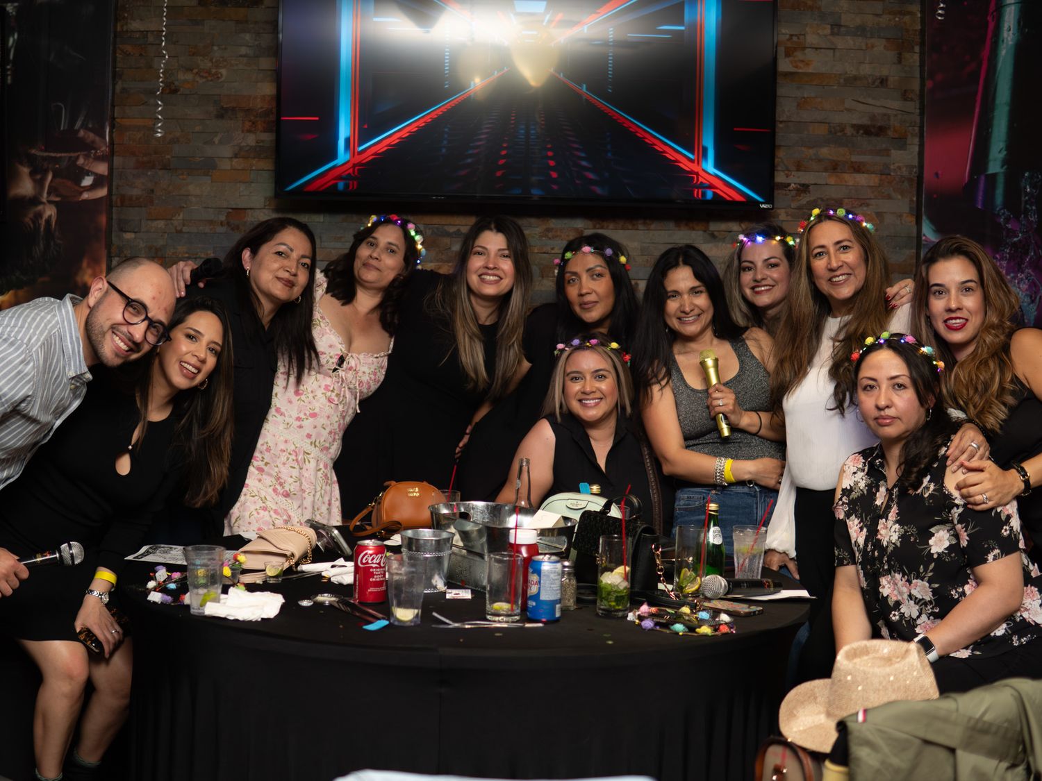 Group of friends posing together at a restaurant table during a celebration, smiling for a photo.