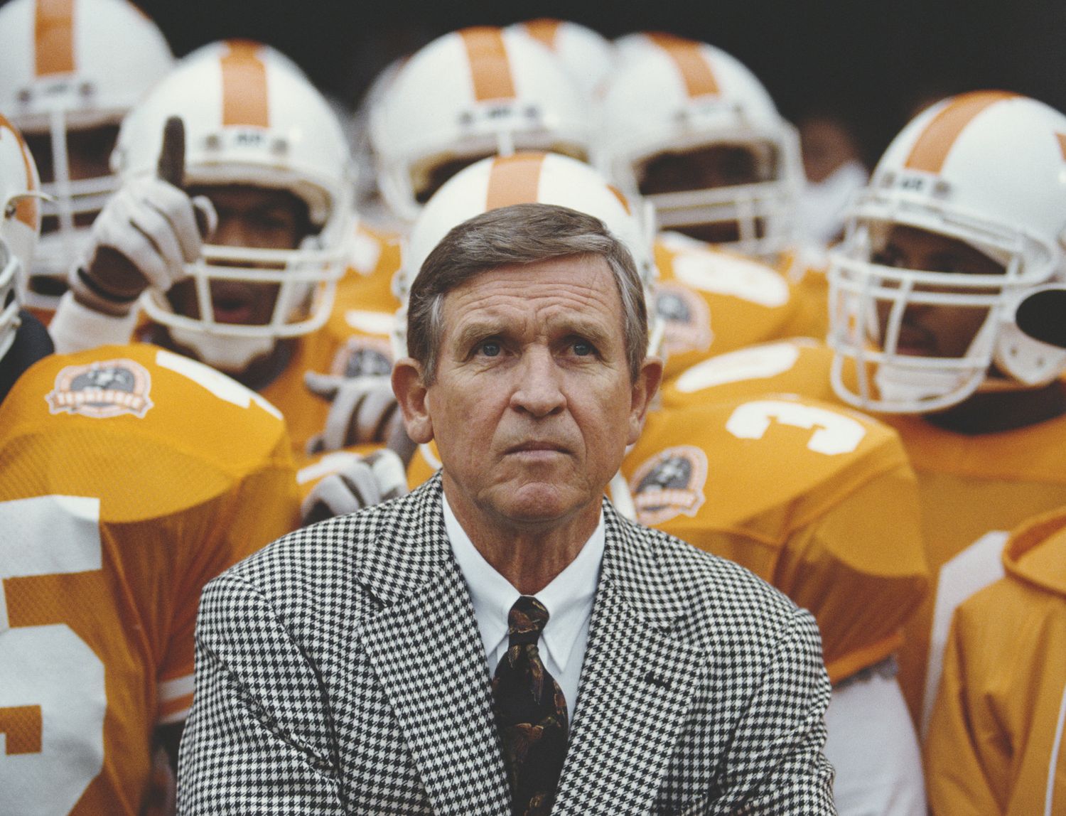 Tennessee football fans in the stands with orange team jerseys and checkered patterns visible.
