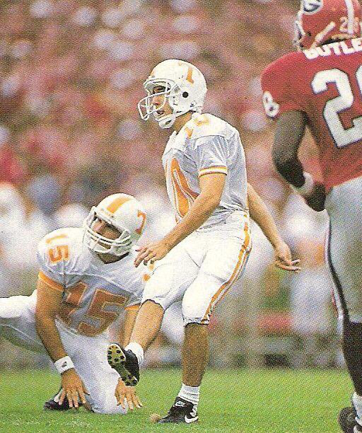 Tennessee Volunteers football player kicks during a game against Georgia Bulldogs in a packed college stadium.