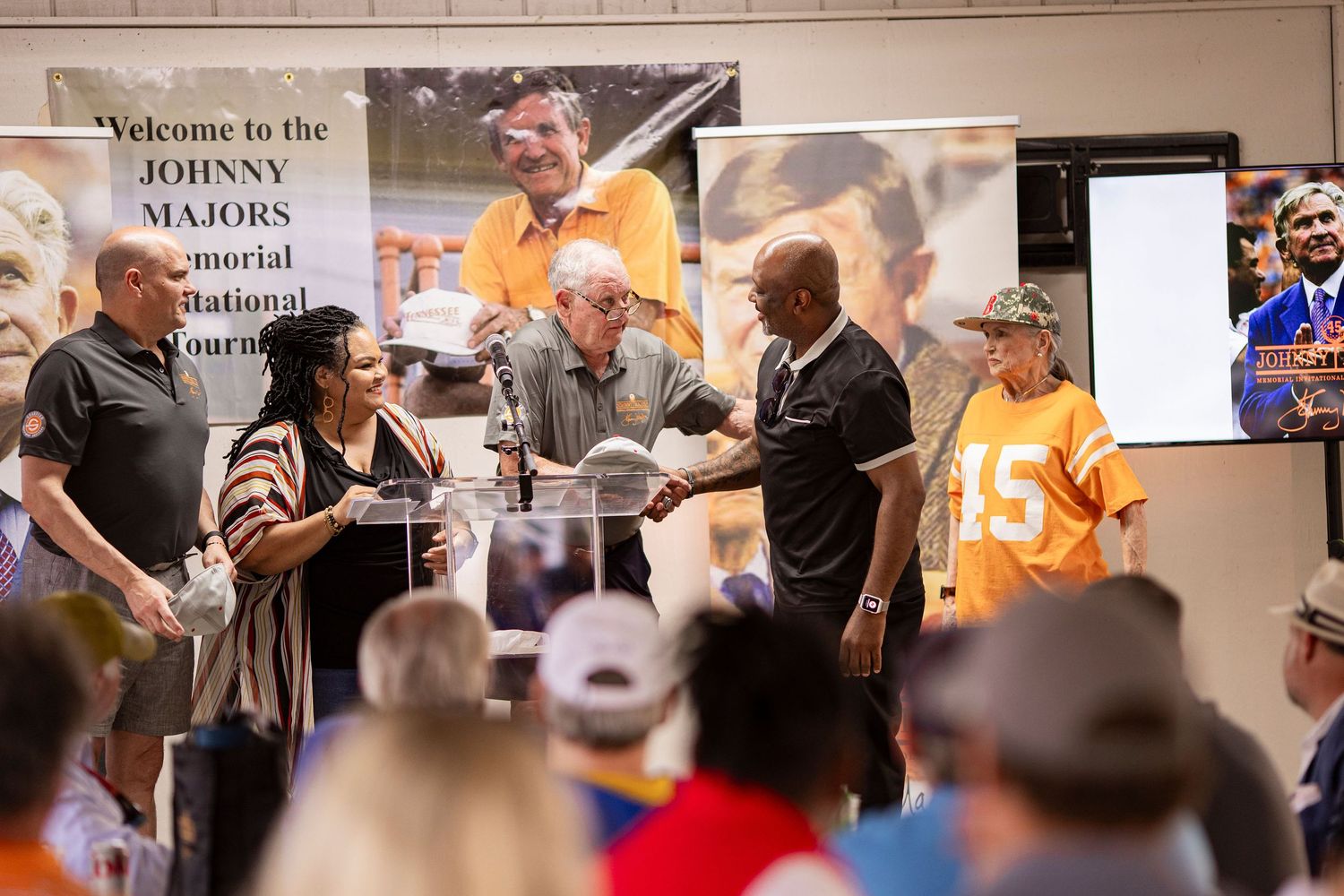 People gathered at the Johnny Majors Memorial National Tournament event, with attendees in Tennessee orange shirts.