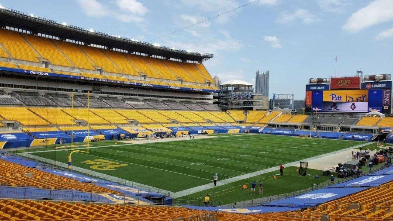 Aerial view of Acrisure Stadium in Pittsburgh, PA, showing the green field and yellow seats on a sunny day.