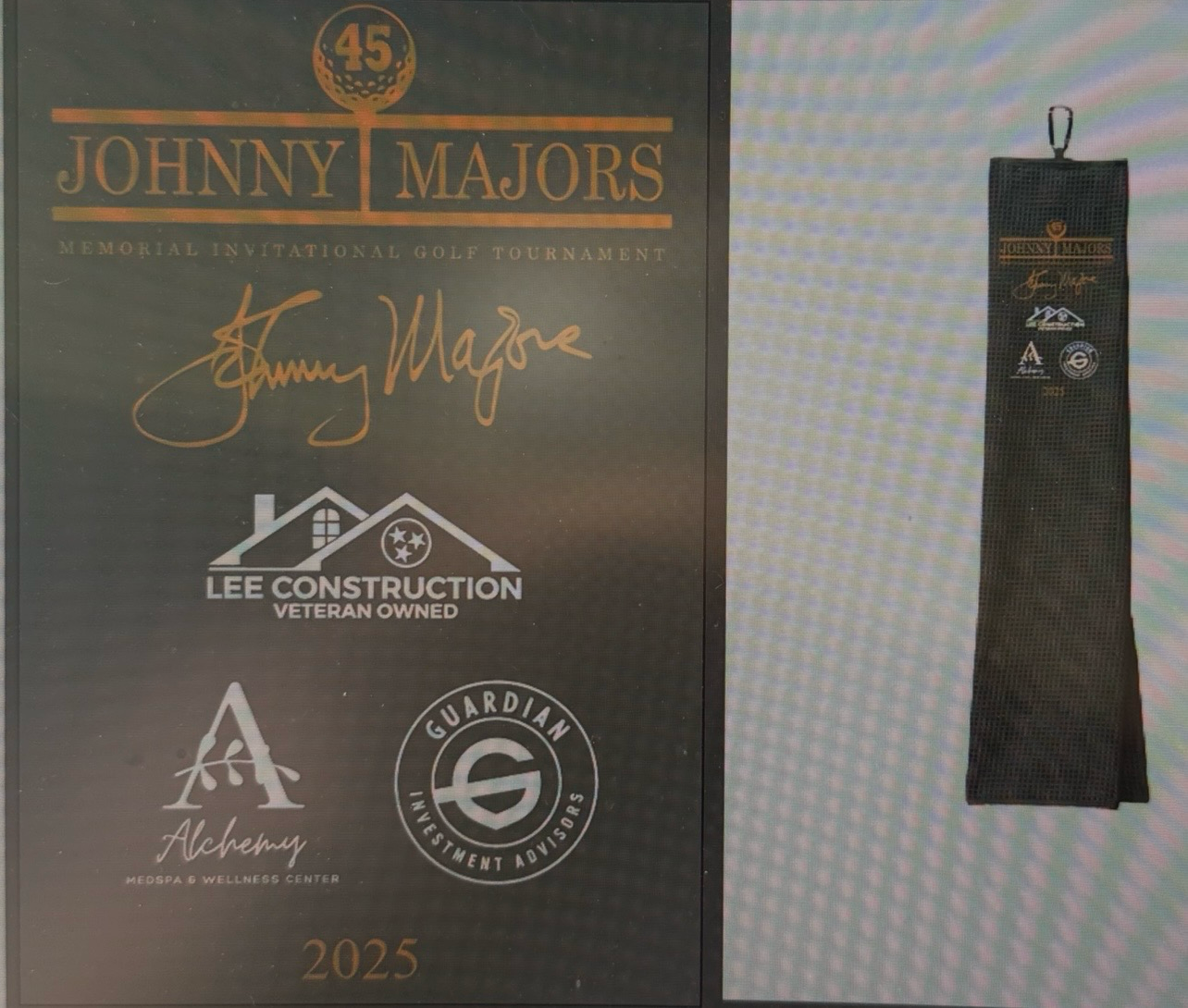 2025 Johnny Majors golf tournament plaque with Lee Construction and Guardian sponsors, displayed alongside a dark embroidered golf towel.