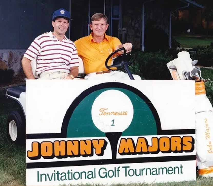 Two men pose on a golf cart at the Johnny Majors Invitational Golf Tournament in Tennessee.