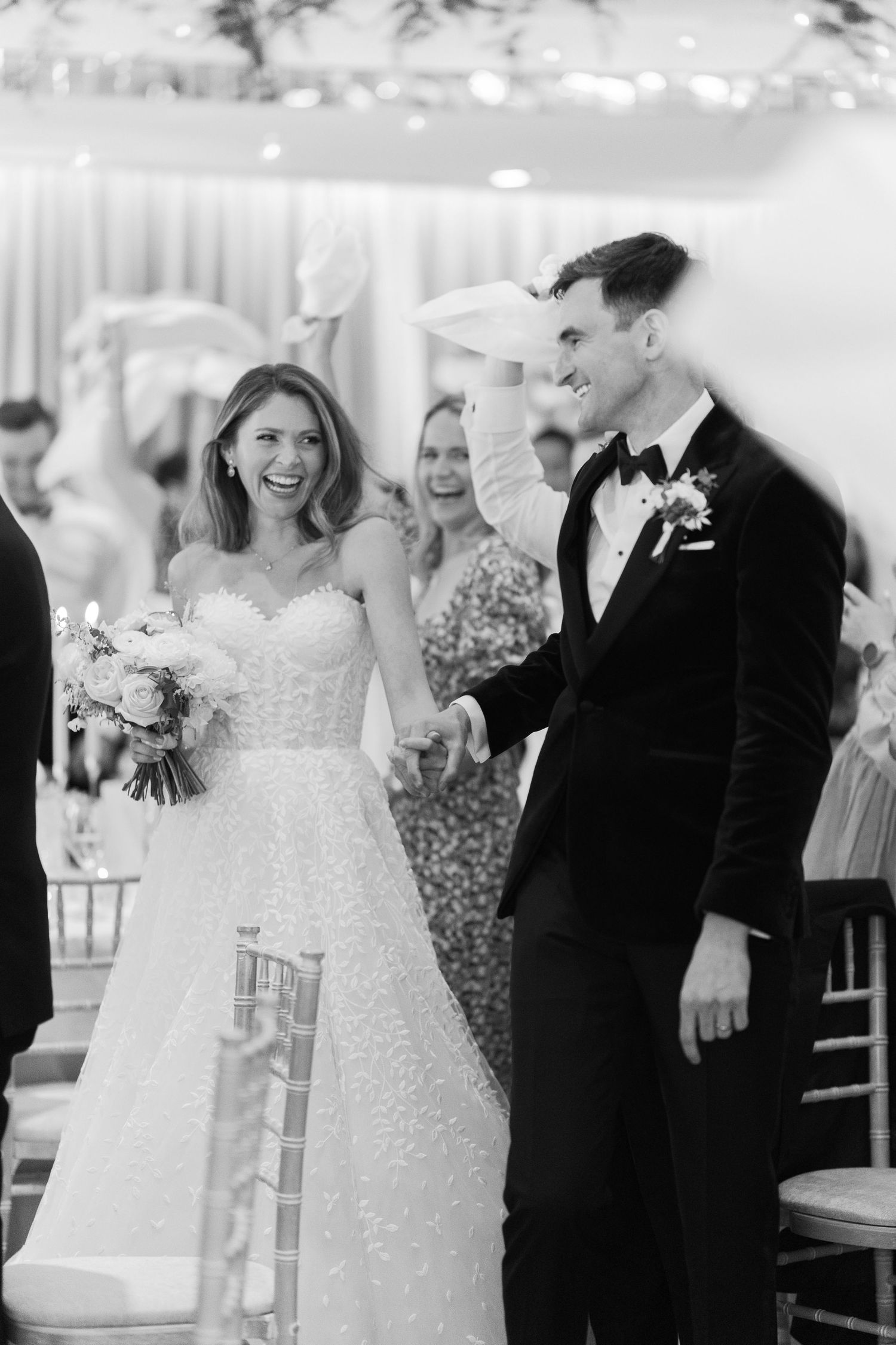 Black and white photo of a joyful bride and groom walking down the aisle after their wedding ceremony.