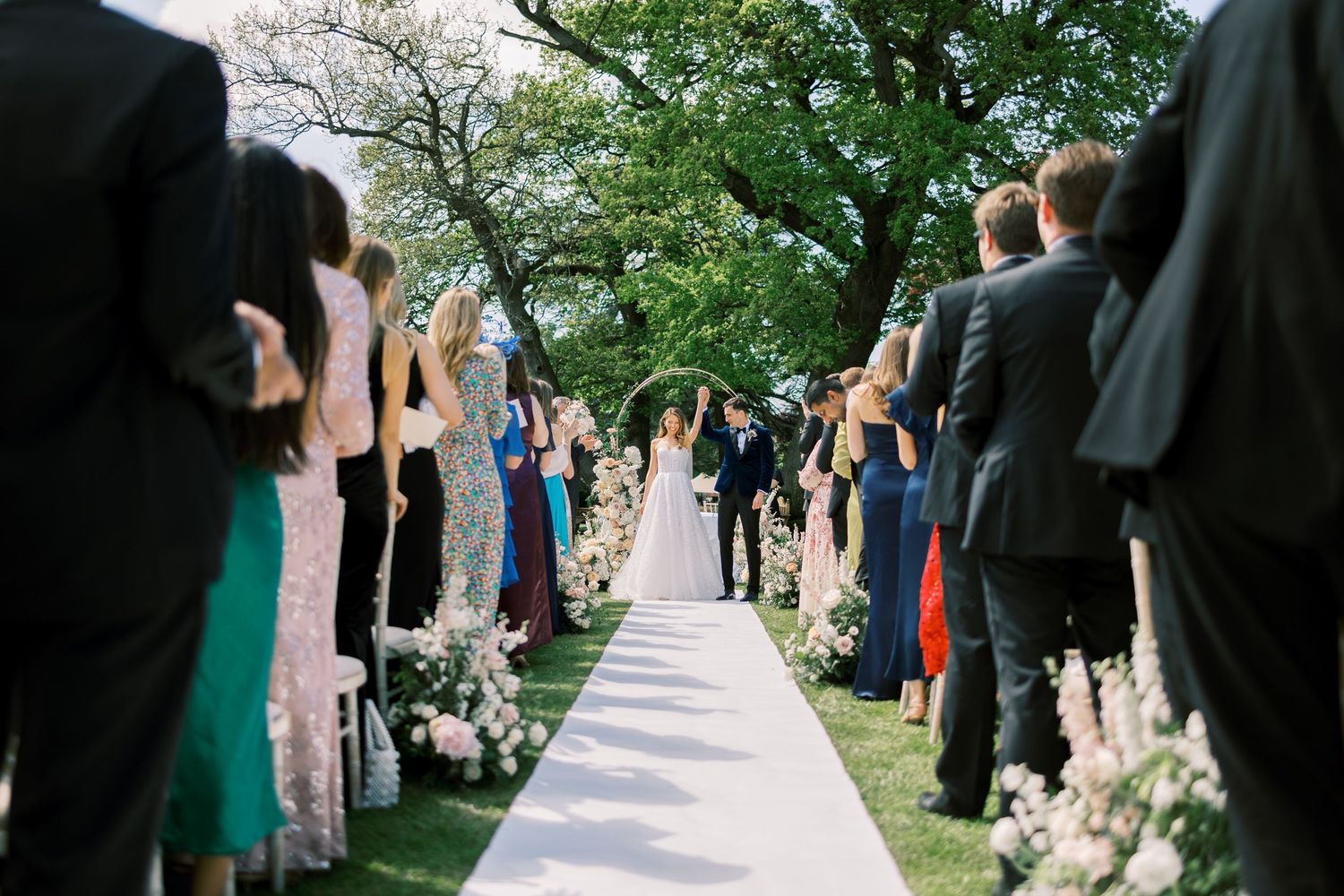 Guests standing as bride and groom walk back down wedding aisle.