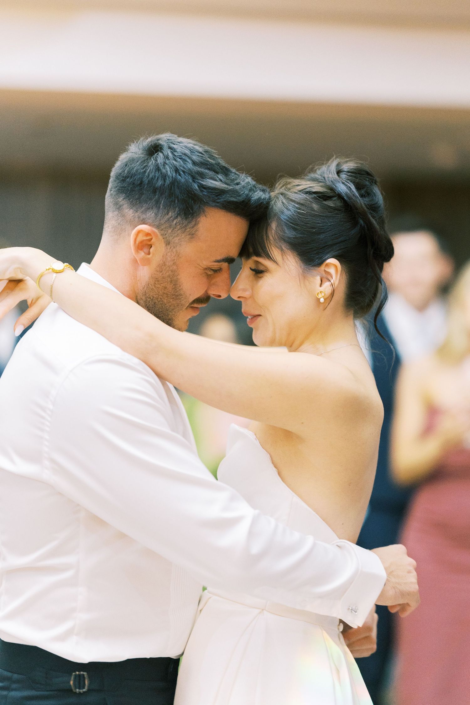 Bride and groom share an intimate first dance, foreheads touching tenderly at their wedding reception.