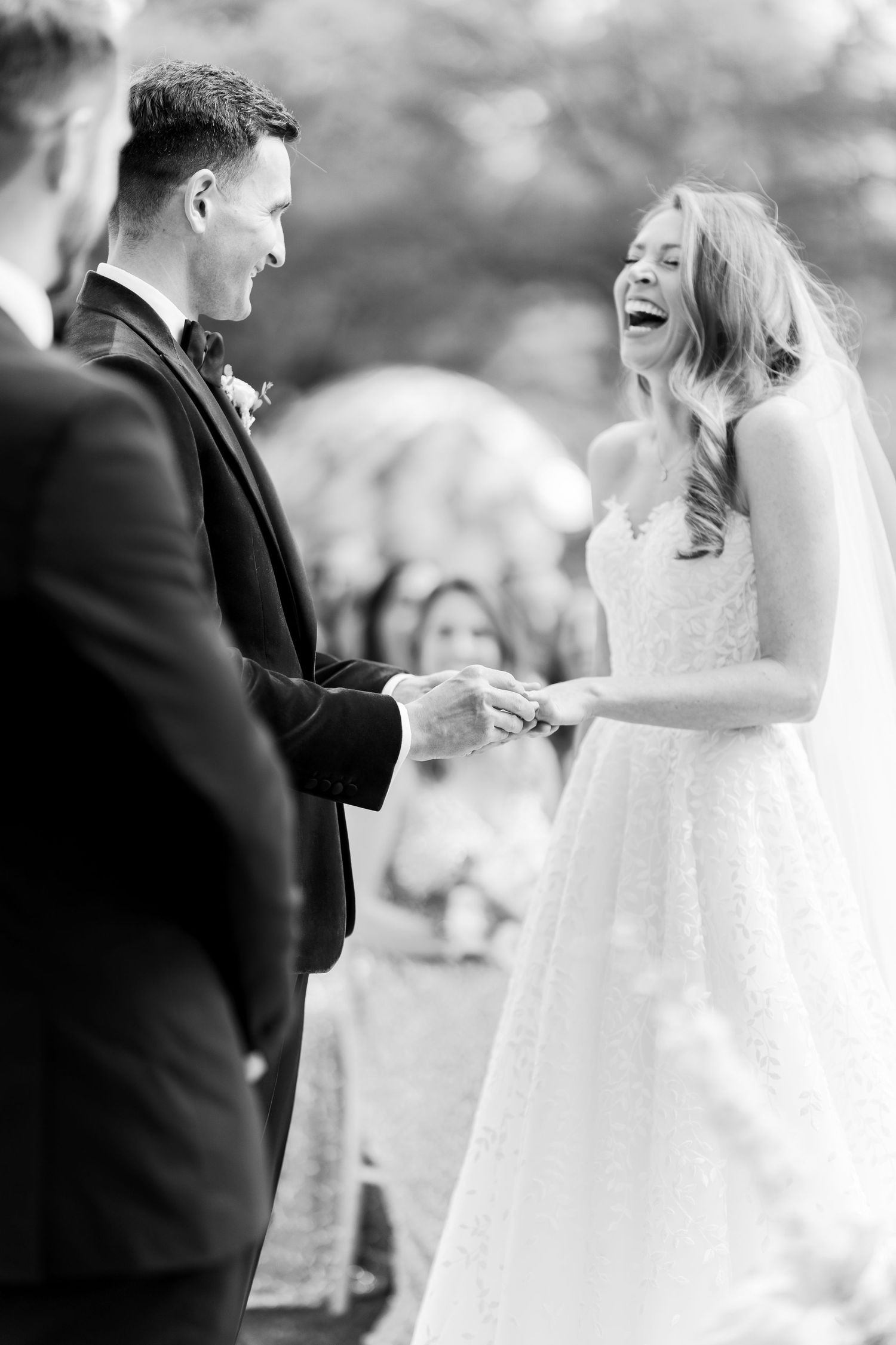 Black and white photo of bride laughing during ring exchange ceremony.