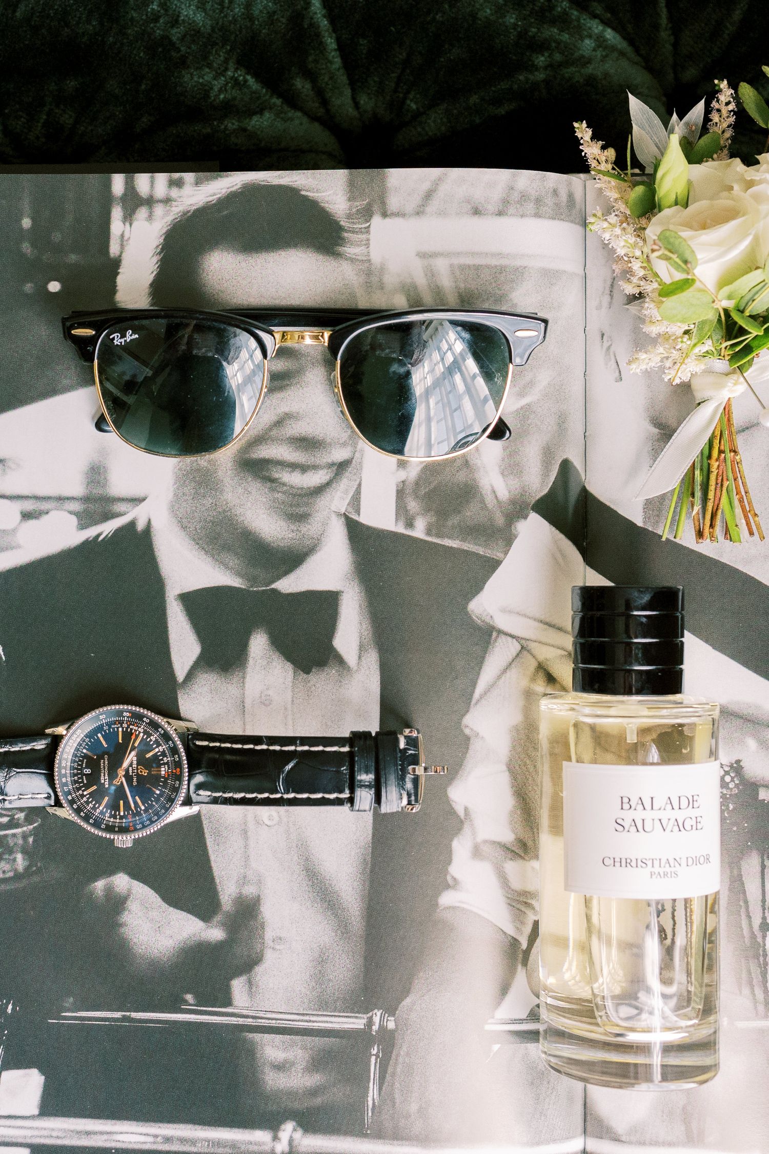Ray-Ban sunglasses, luxury watch, and Christian Dior Balade Sauvage cologne on a black and white wedding photo.