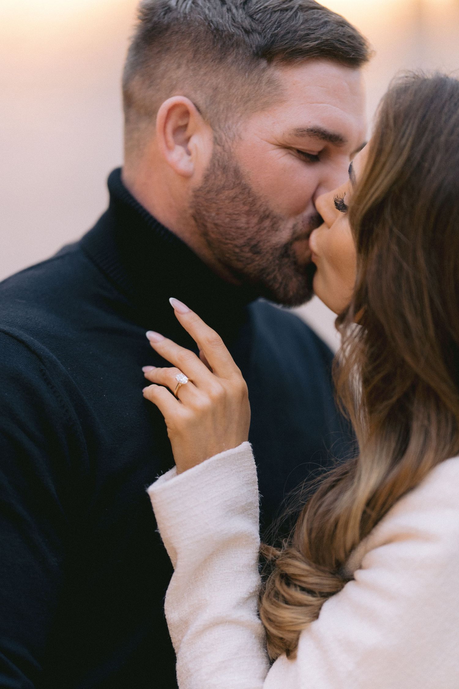 Couple sharing a passionate kiss with diamond engagement ring visible on woman's hand.