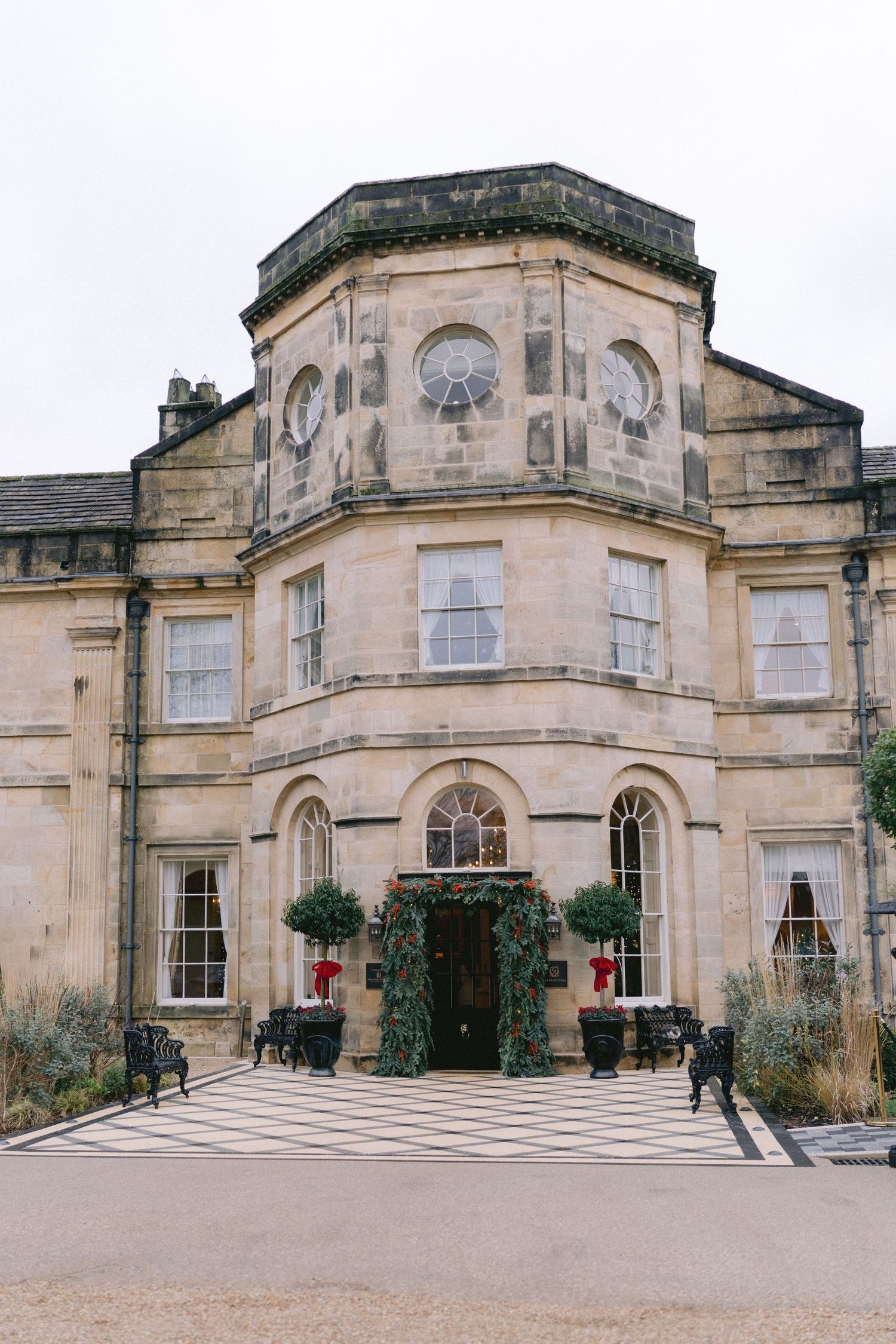 Grand historic stone manor house, Grantley Hall, with Christmas wreath decorations at the entrance doorway.
