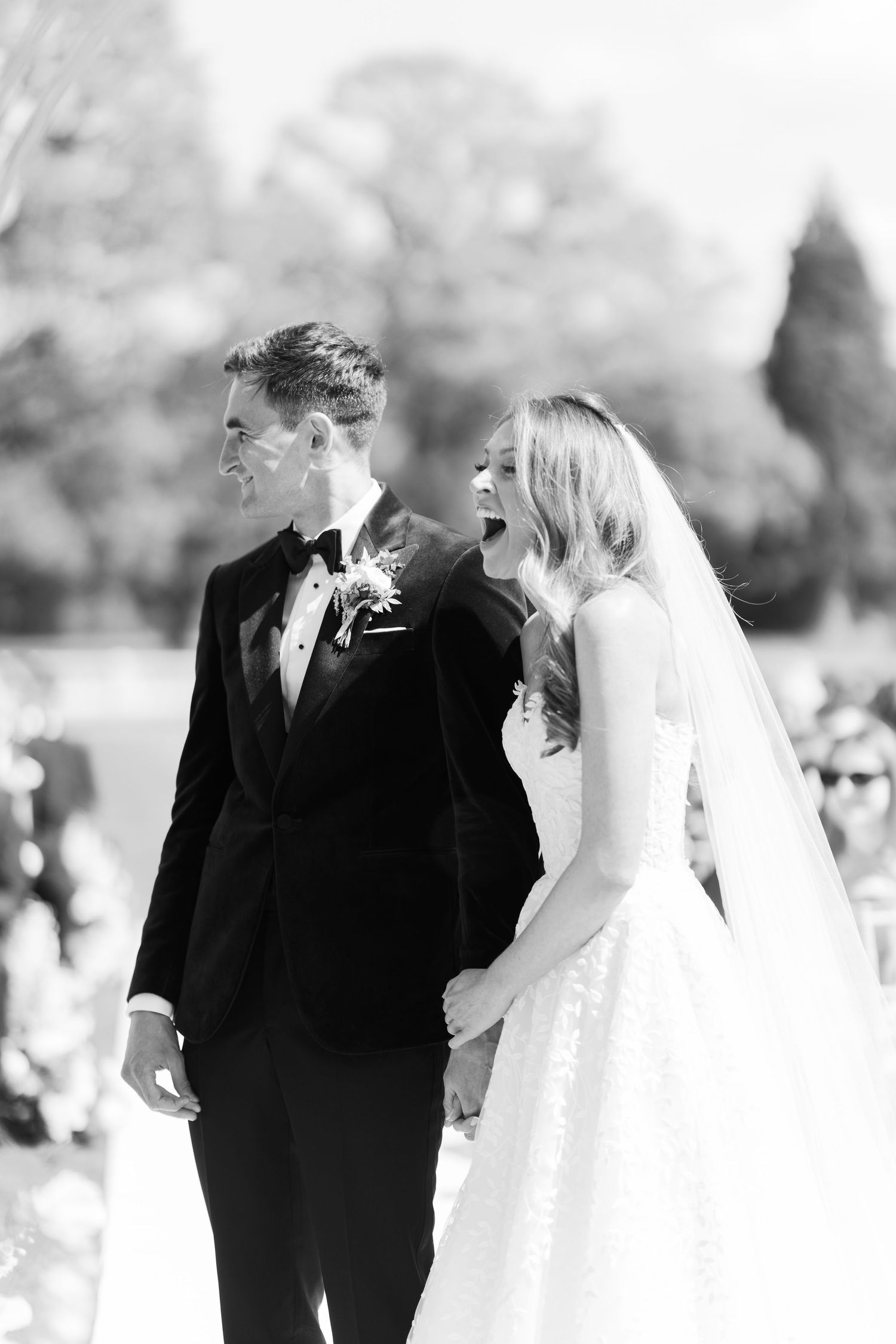 Black and white photo of bride and groom laughing at altar.
