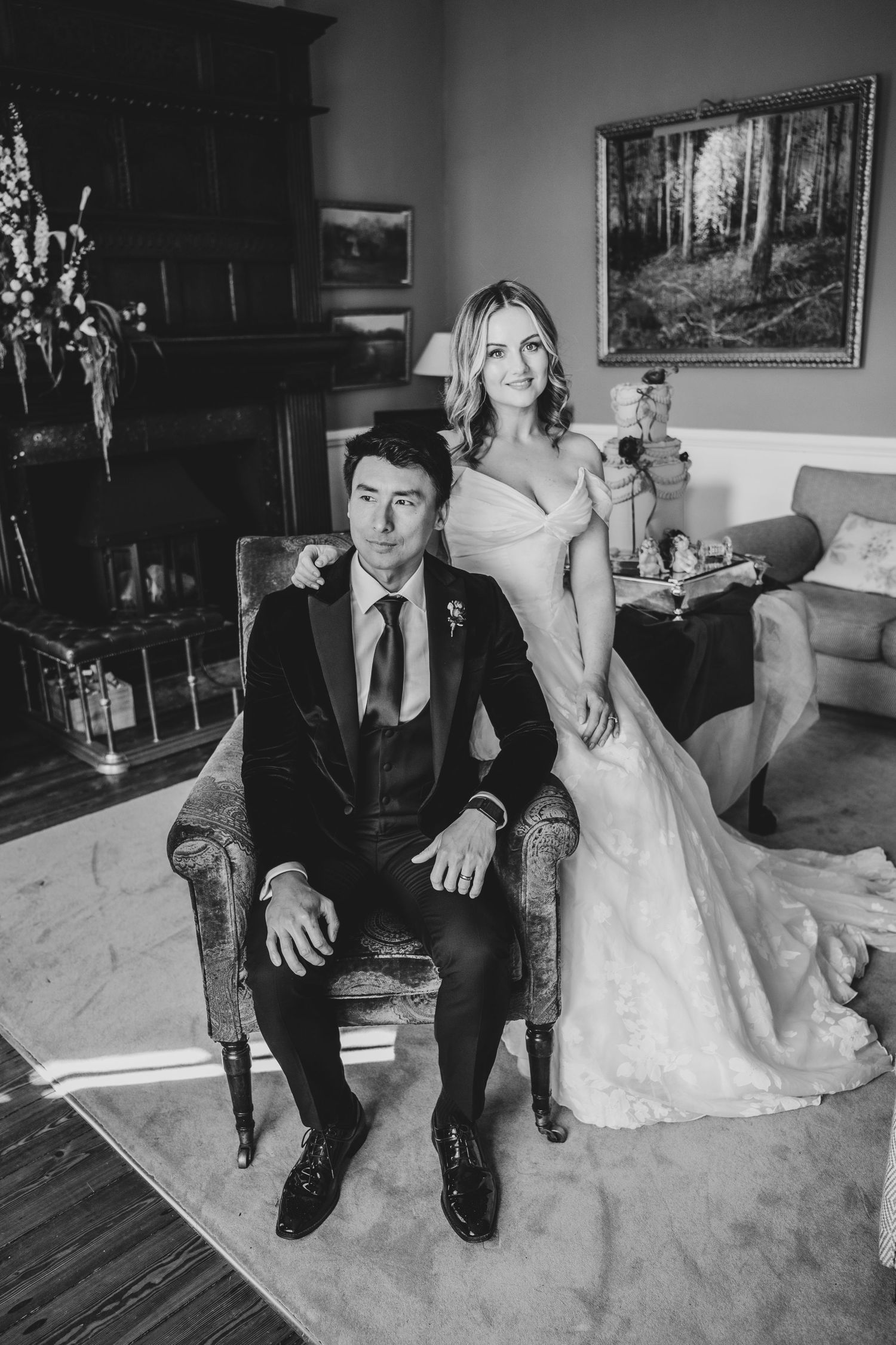 Black and white portrait of bride and groom posing elegantly in a classic interior wedding setting.