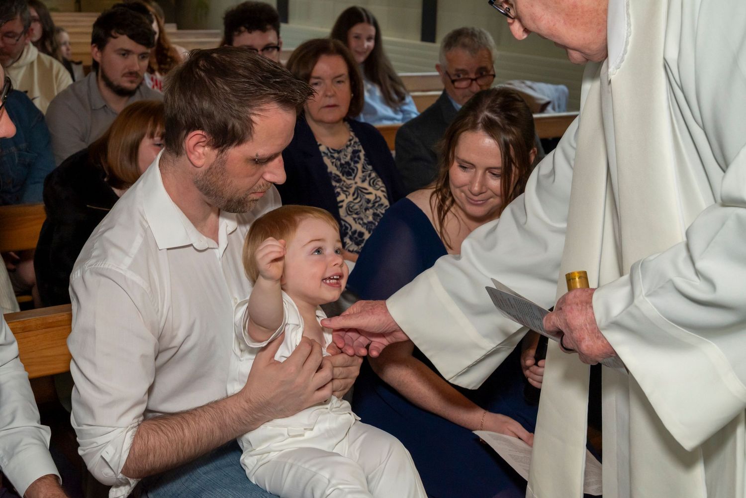 A priest blesses a young child during a christening ceremony in a church.