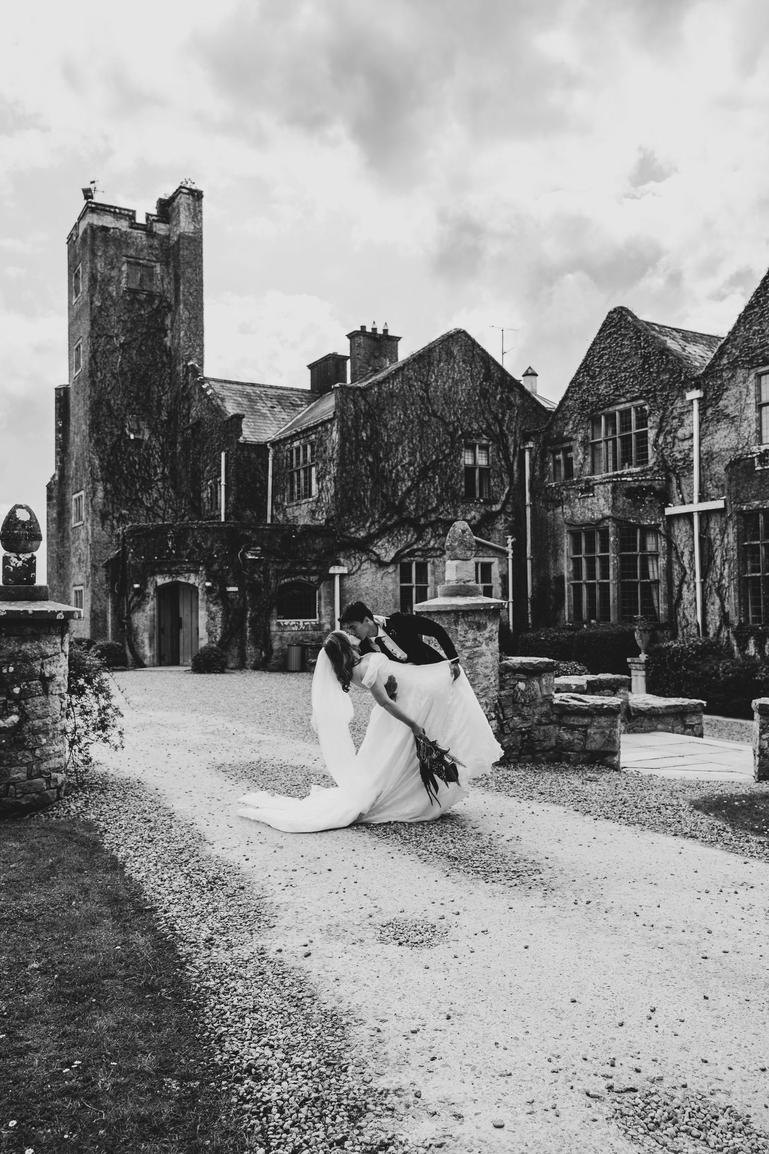 Black and white photo of bride and groom embracing outside a historic castle wedding venue.