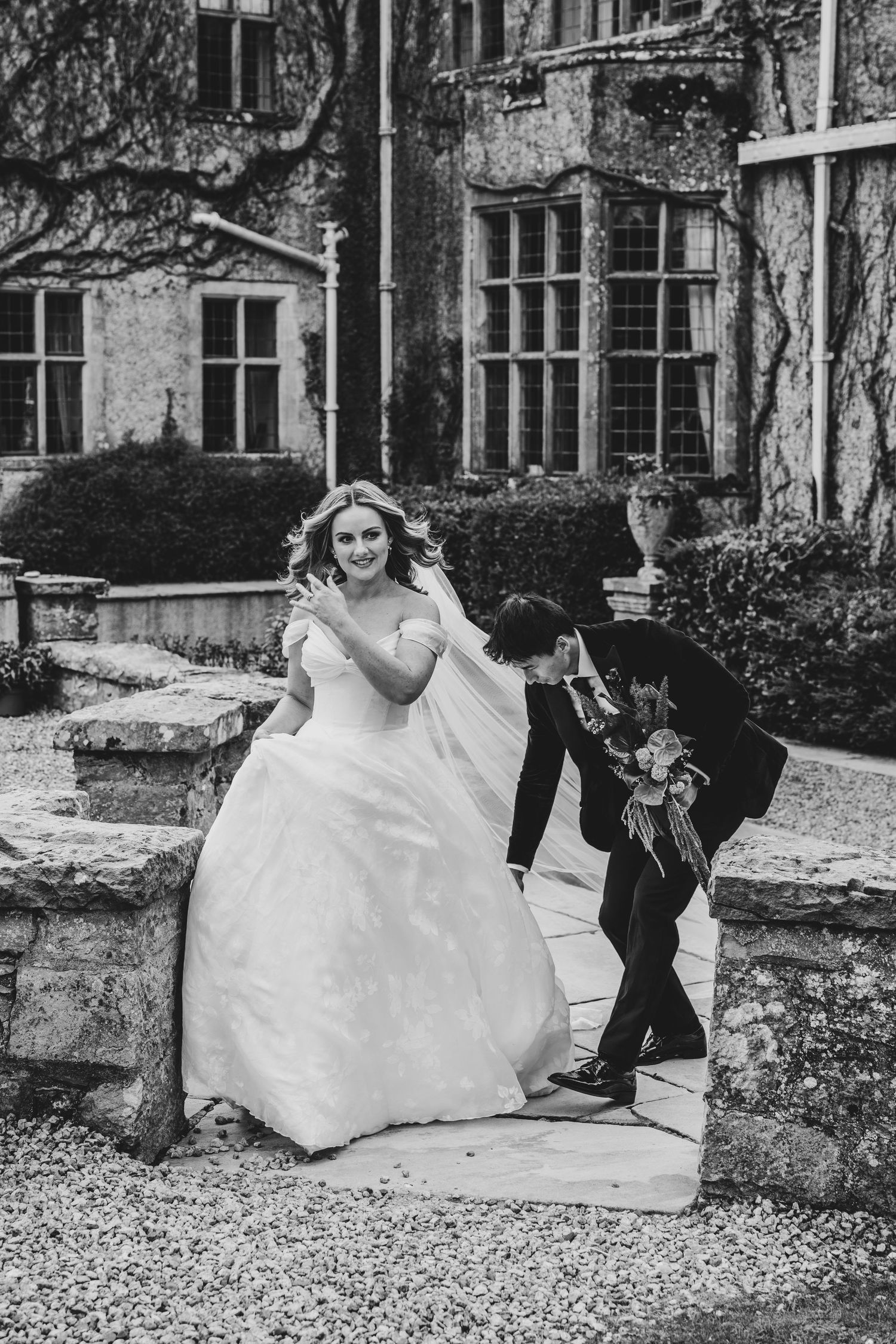 Black and white photo of bride and groom sharing romantic moment outside historic manor wedding venue.