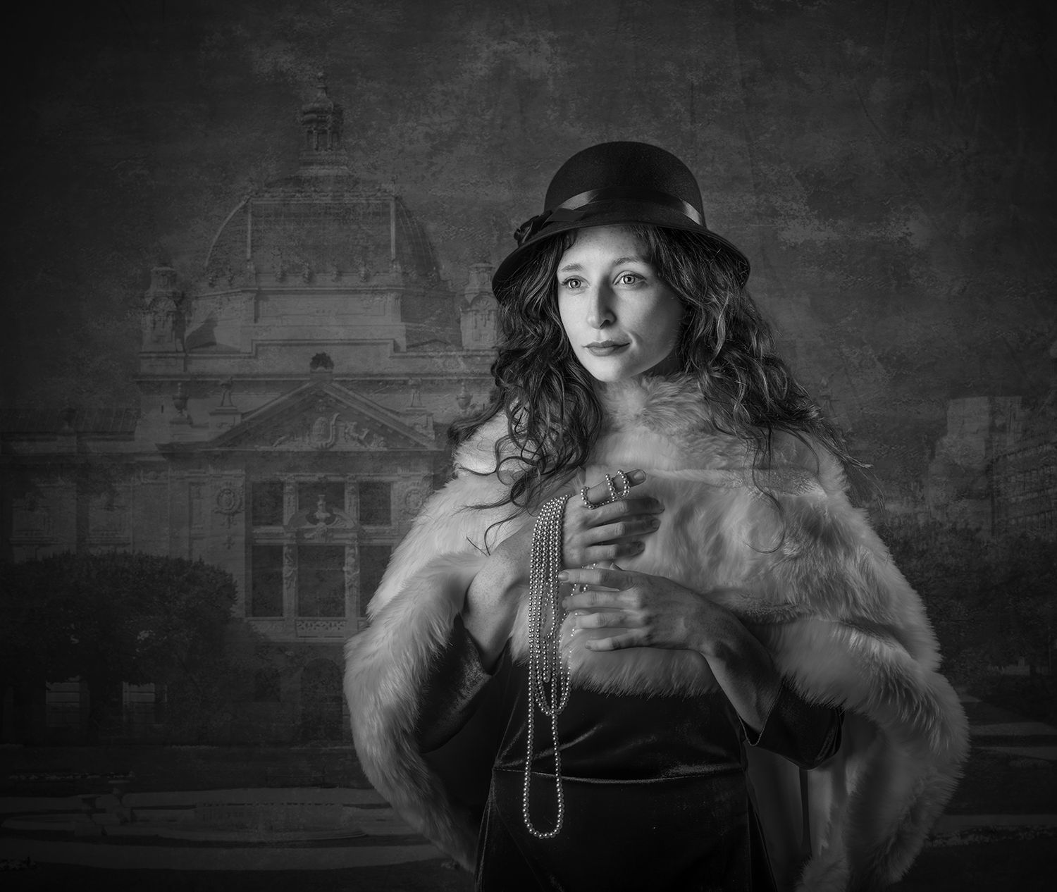 Black and white portrait of a woman in a bowler hat and fur stole, holding beads before a grand building backdrop.