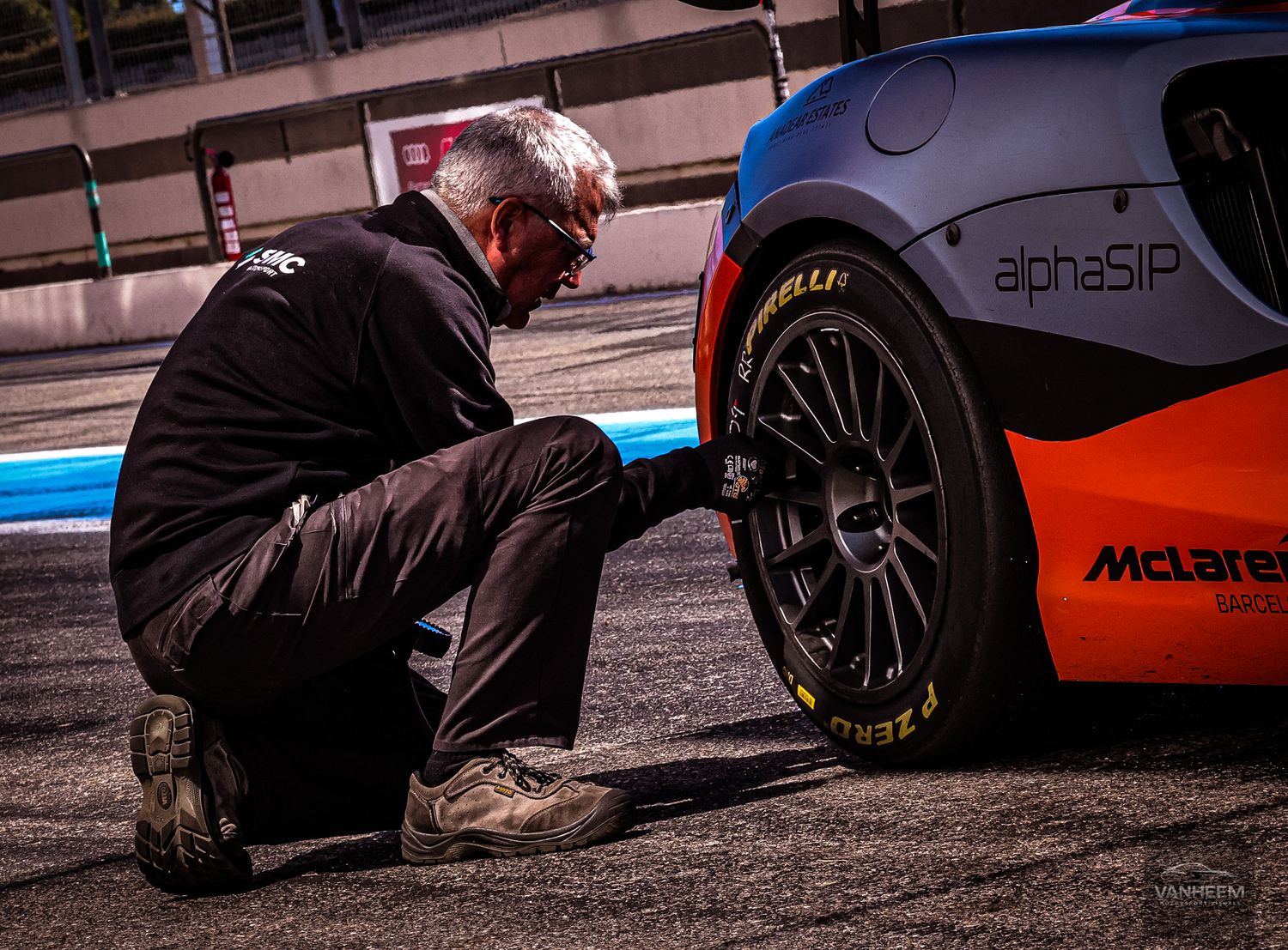 Close-up view of race car tires and mechanics working on vehicle maintenance.